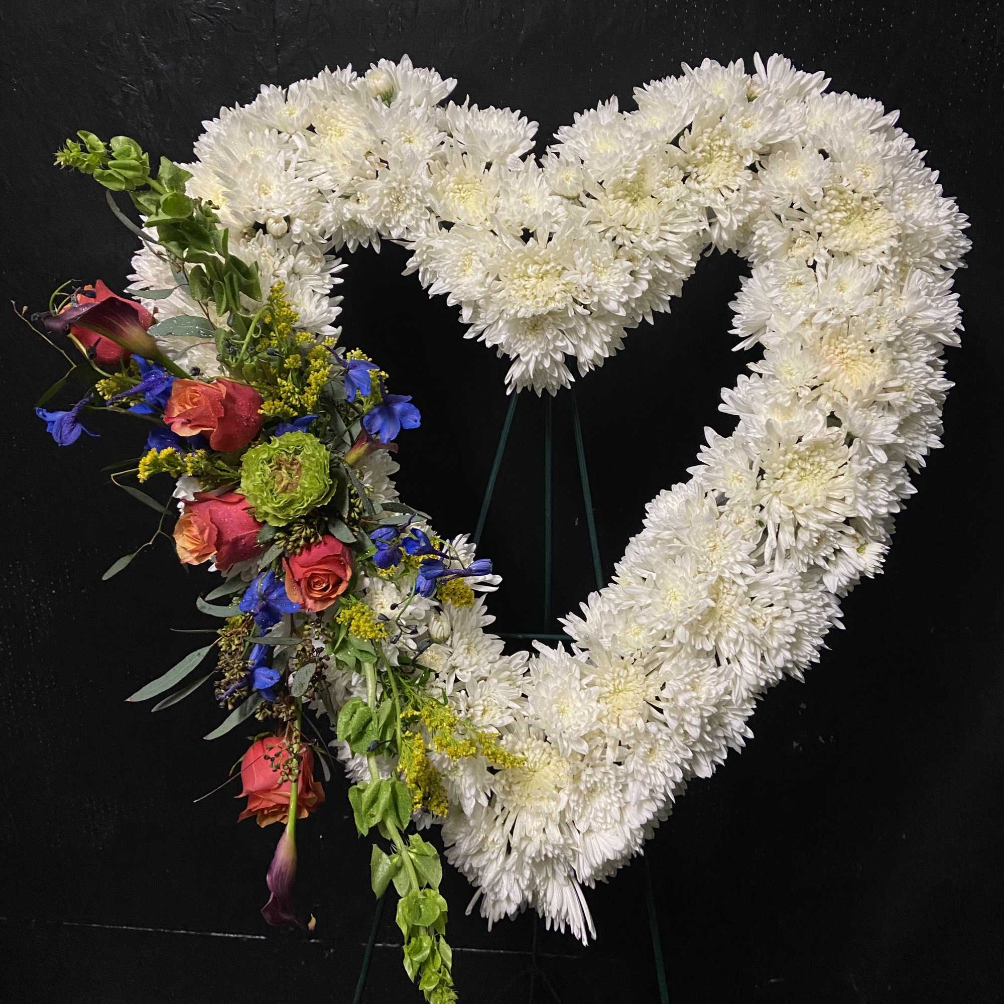 Heart-shaped floral tribute with white chrysanthemums and colorful roses