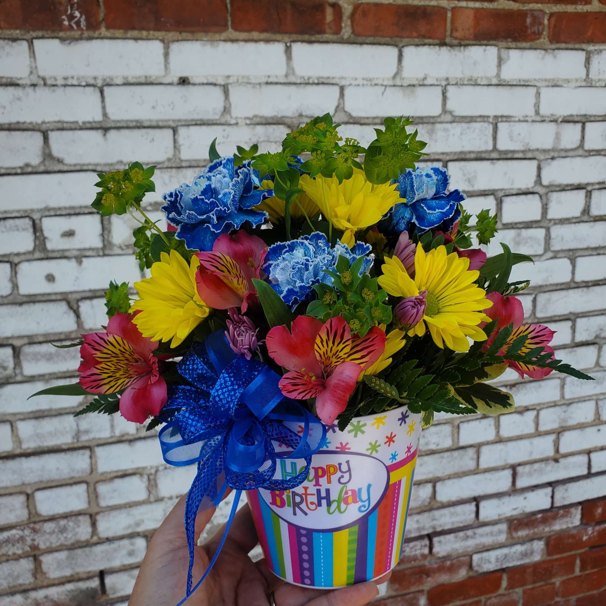 Colorful bouquet in a birthday cup with a blue ribbon