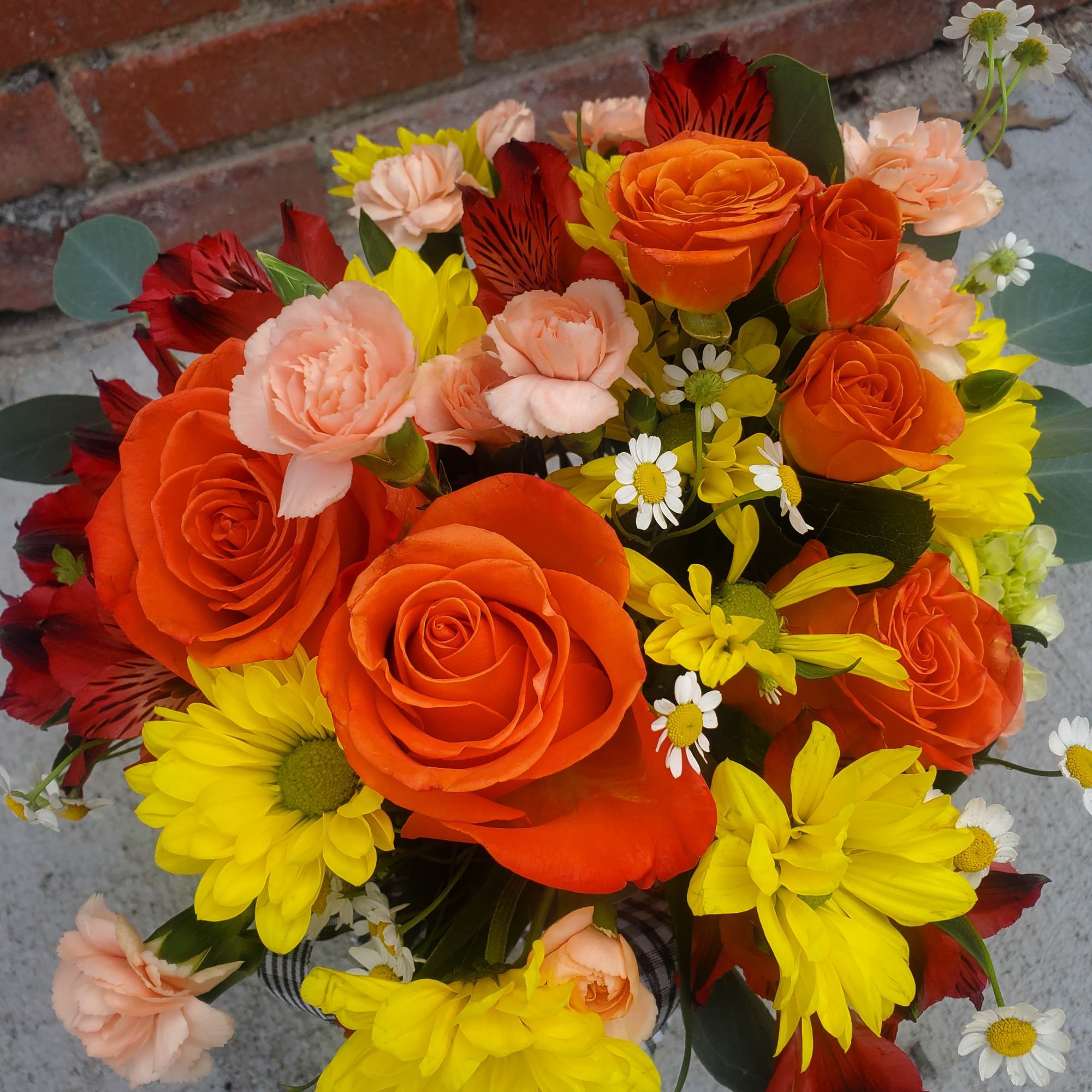 Bouquet of orange roses, yellow daisies, and peach carnations