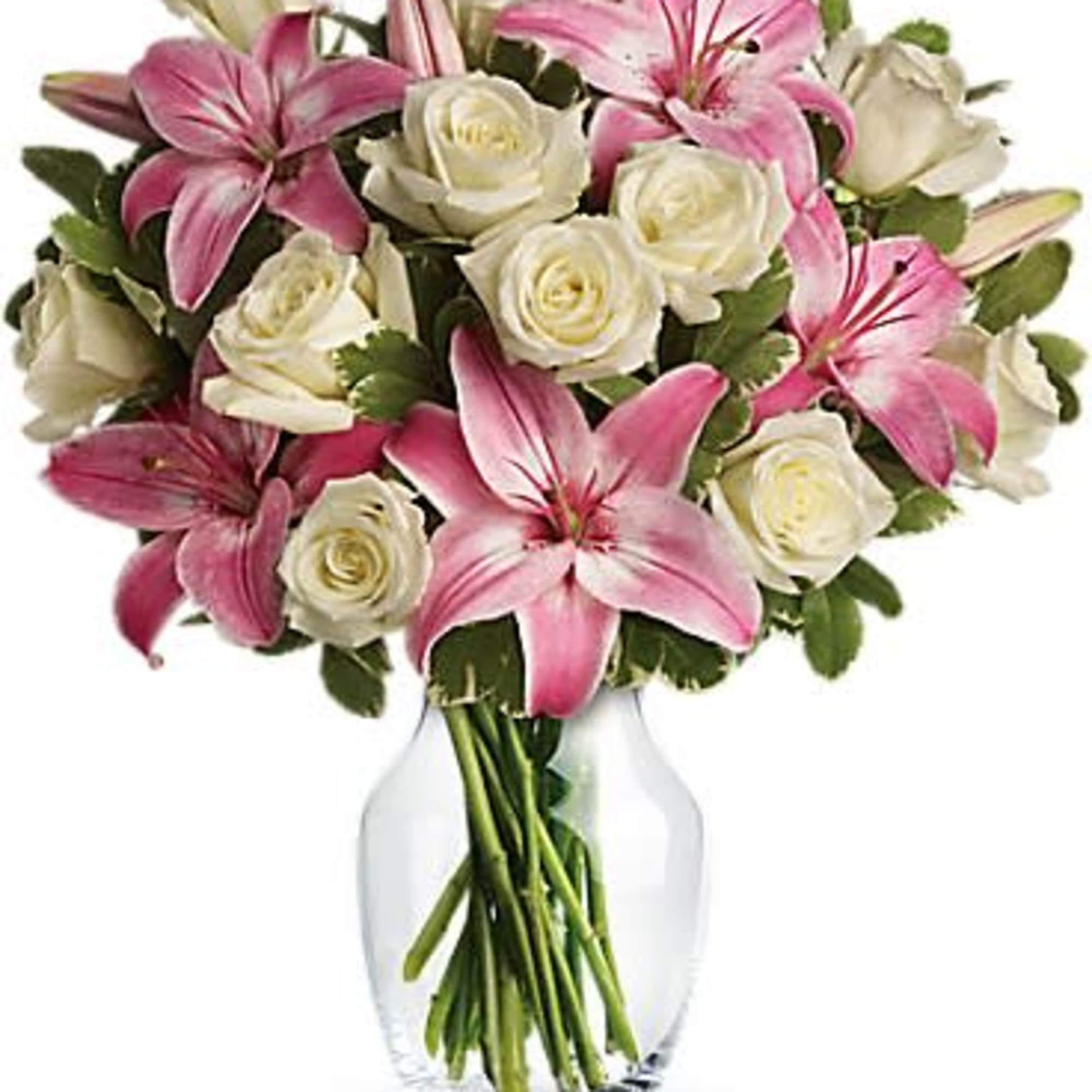 Pink lilies and white roses arranged in a clear glass vase