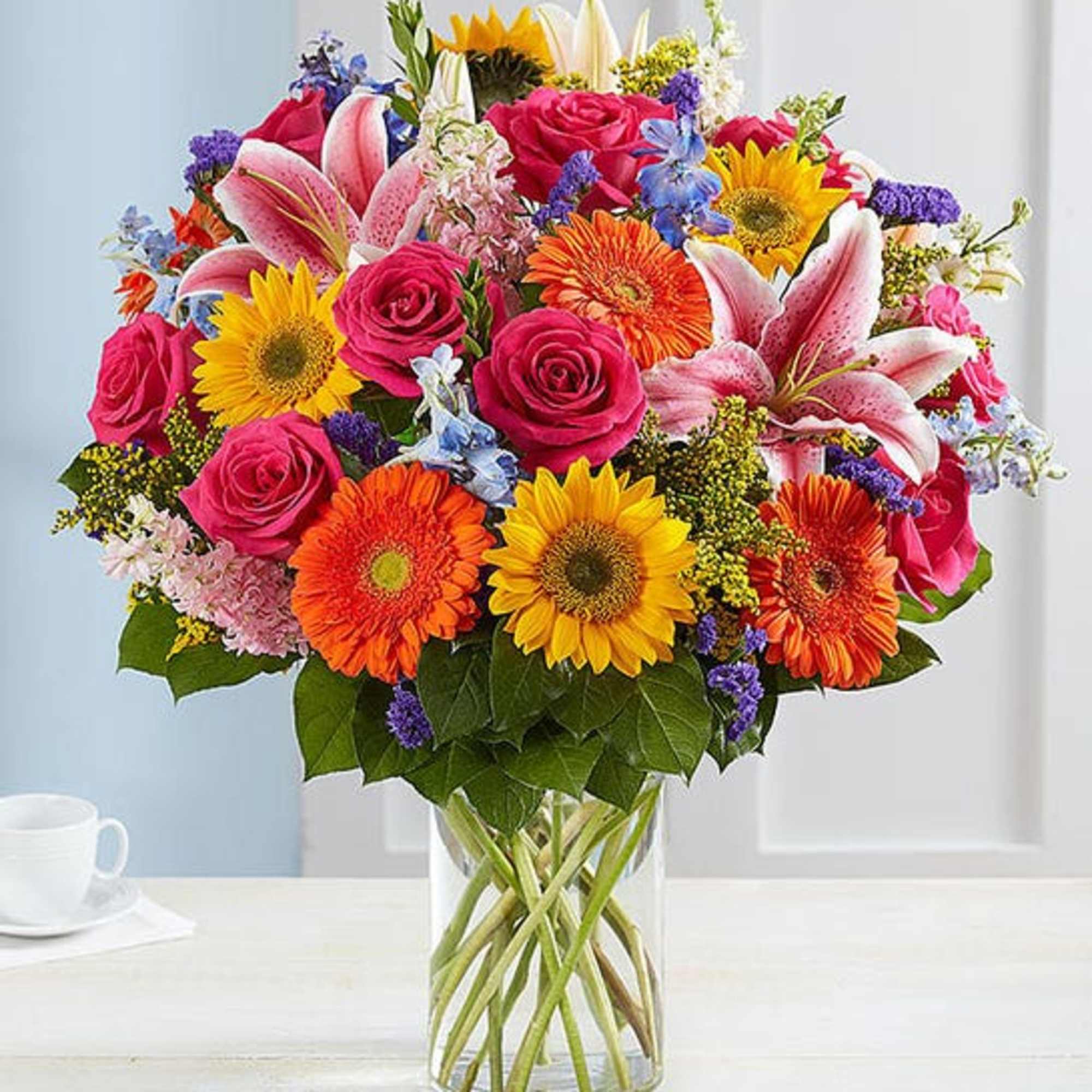 Mixed bouquet of roses, lilies, and gerbera daisies in a glass vase