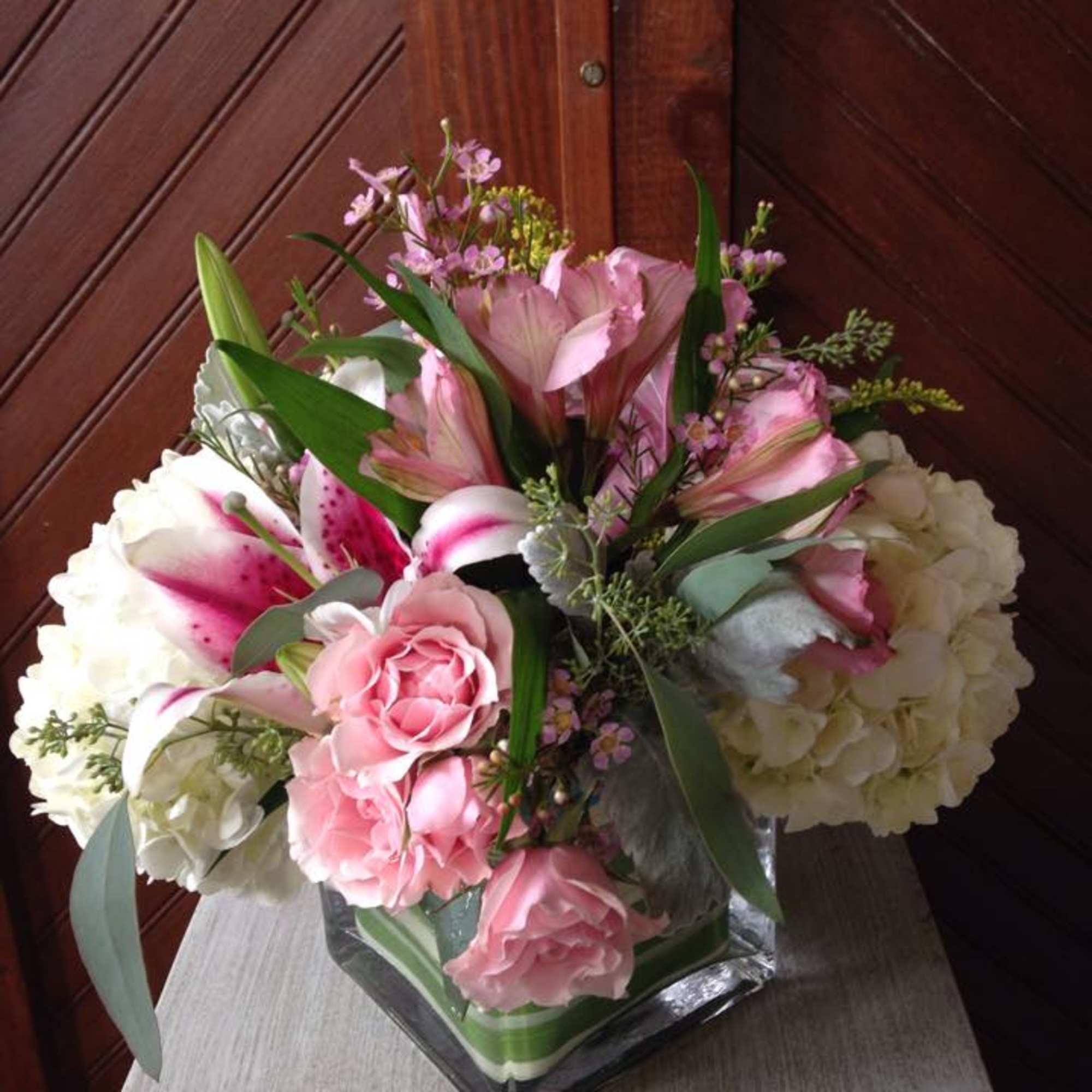Pink and white floral arrangement in a square glass vase