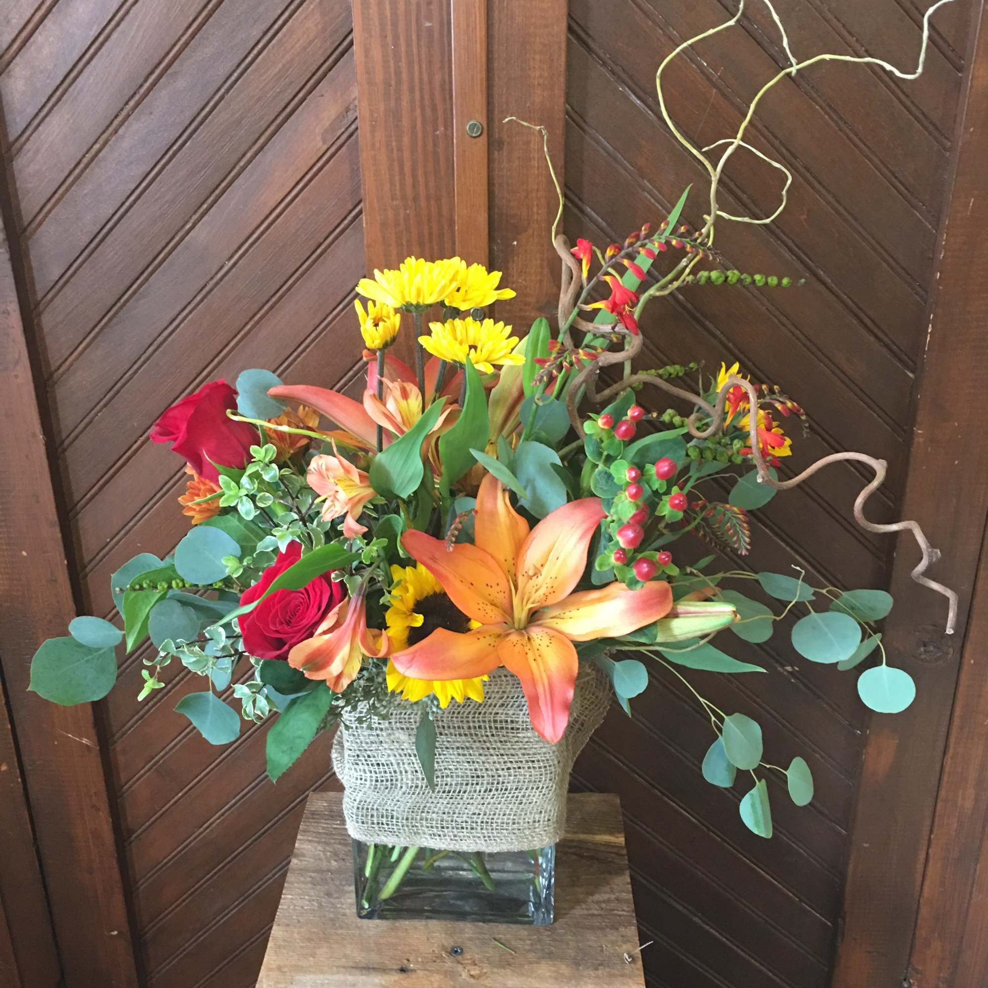 Mixed bouquet with lilies, roses, and yellow daisies in a glass vase
