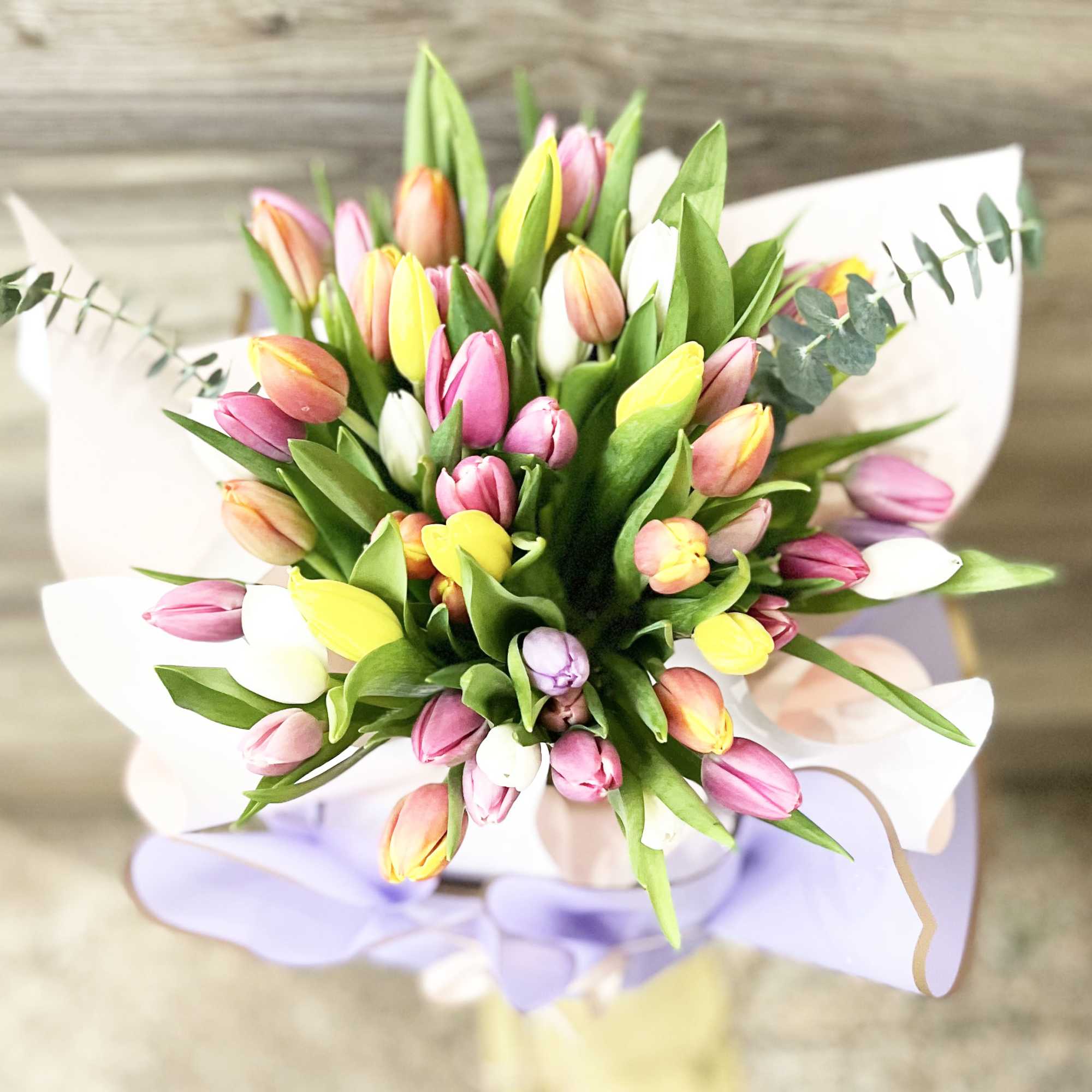 Bouquet of multicolored tulips wrapped in white paper