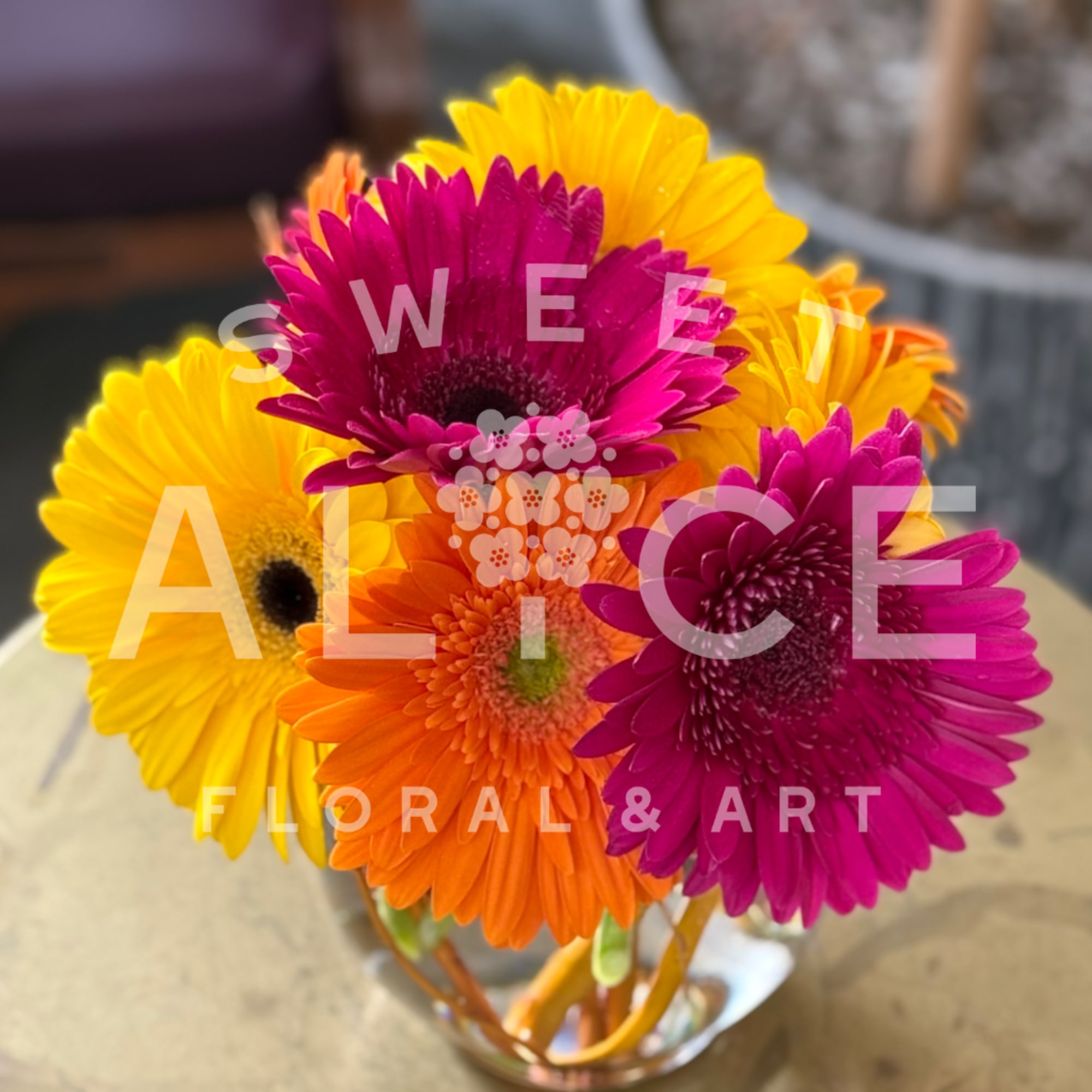 Bright gerbera daisy bouquet in a glass vase with pink, orange, and yellow blooms