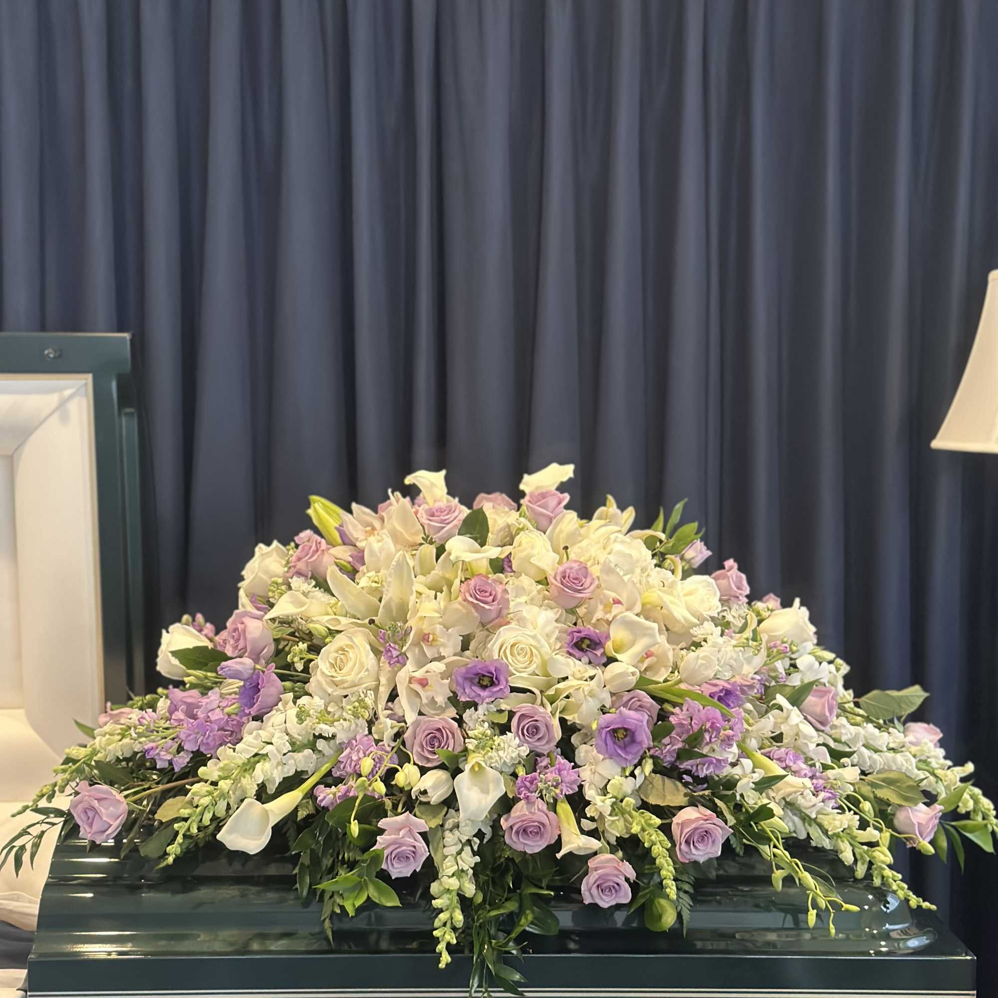 Large pastel floral casket spray with roses, calla lilies, and orchids