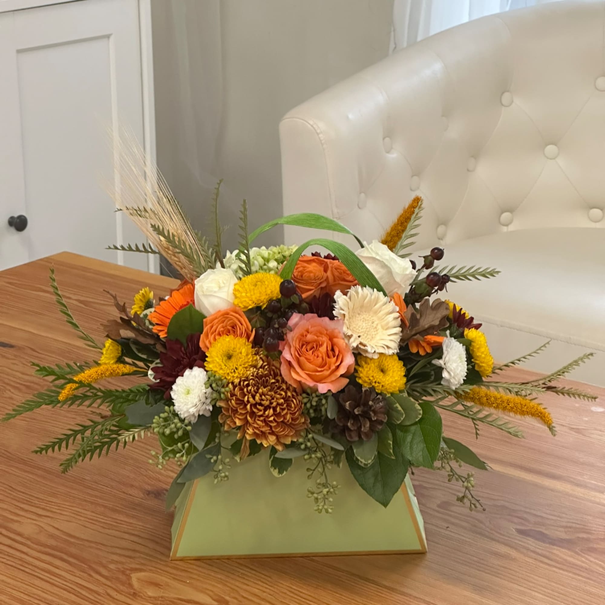 Mixed bouquet of orange, yellow, white, and burgundy flowers in a green box