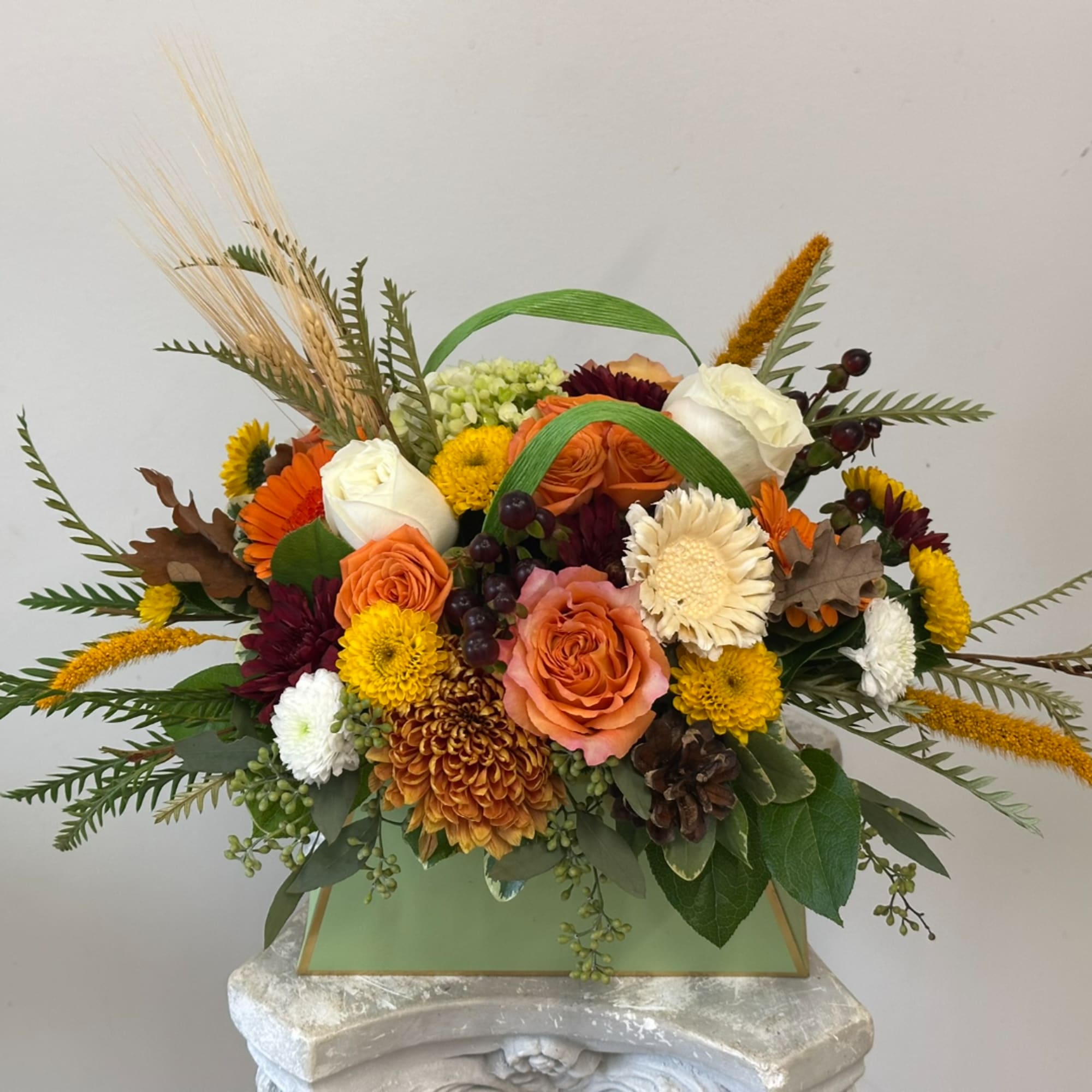 Autumn bouquet with orange and white roses in a green box