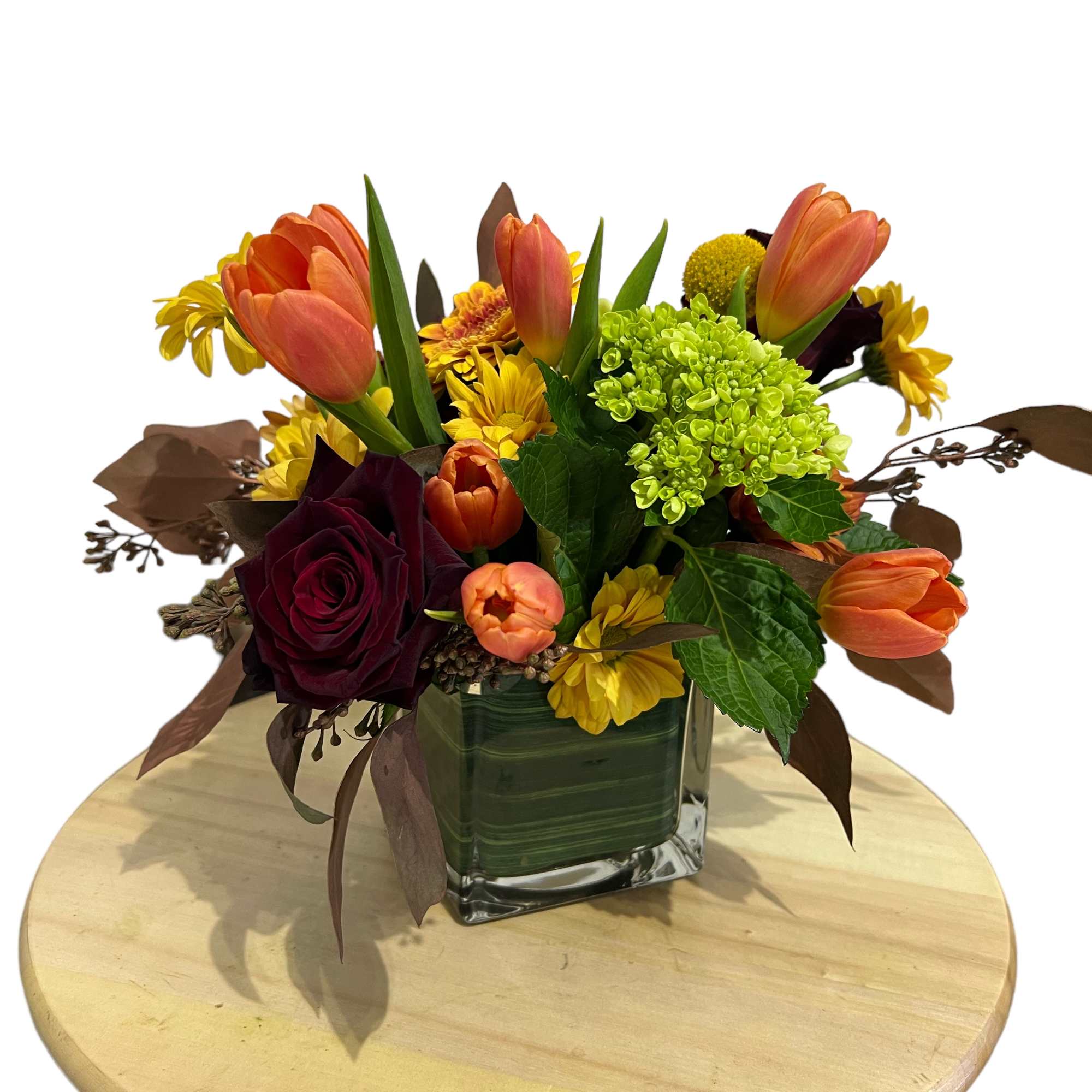 Orange tulips and mixed flowers arranged in a square glass vase
