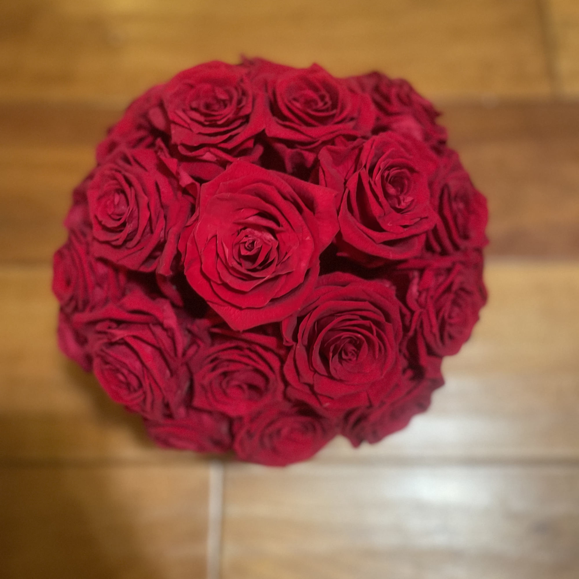 Round bouquet of red roses on a wooden floor
