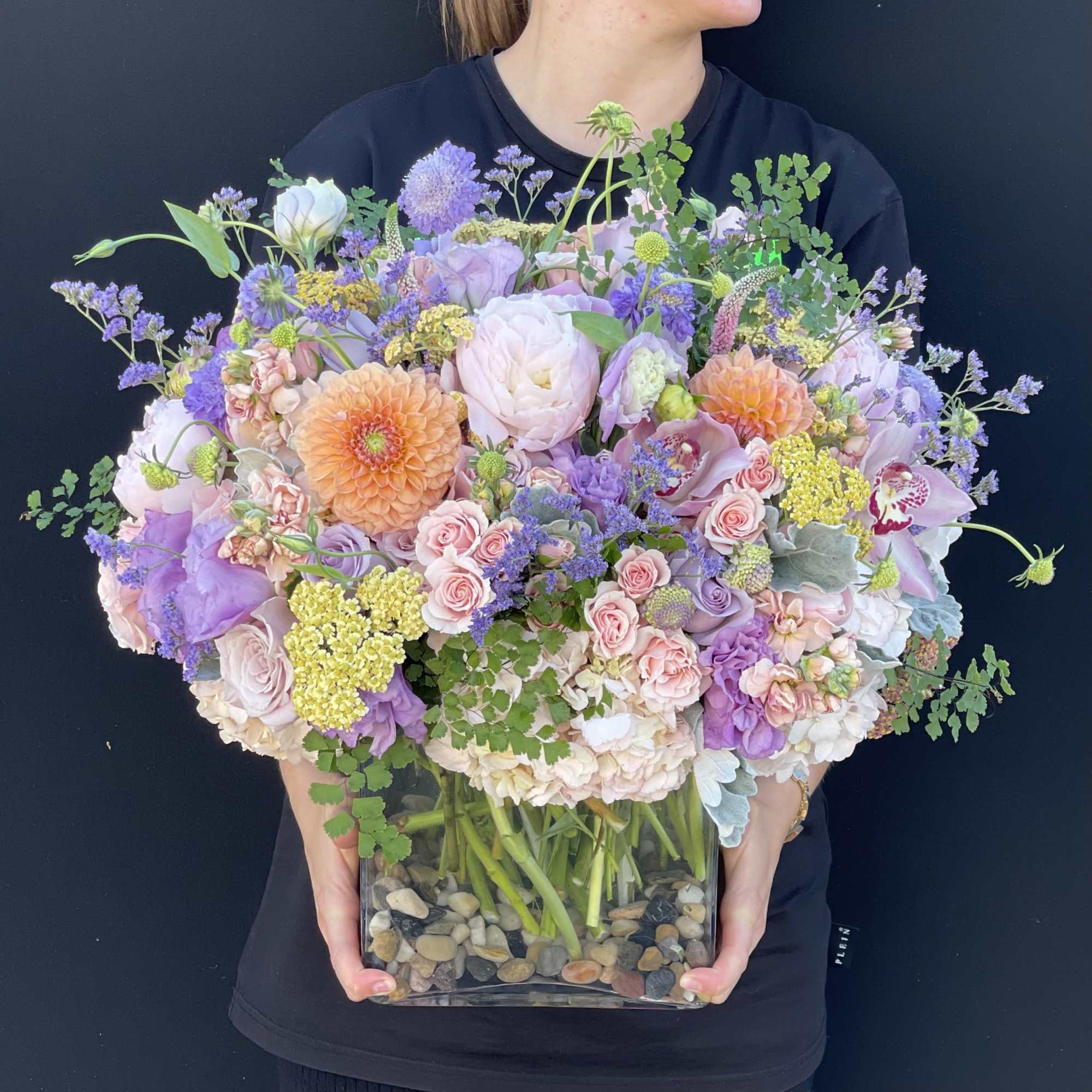 Large pastel bouquet in a clear square vase with pebbles