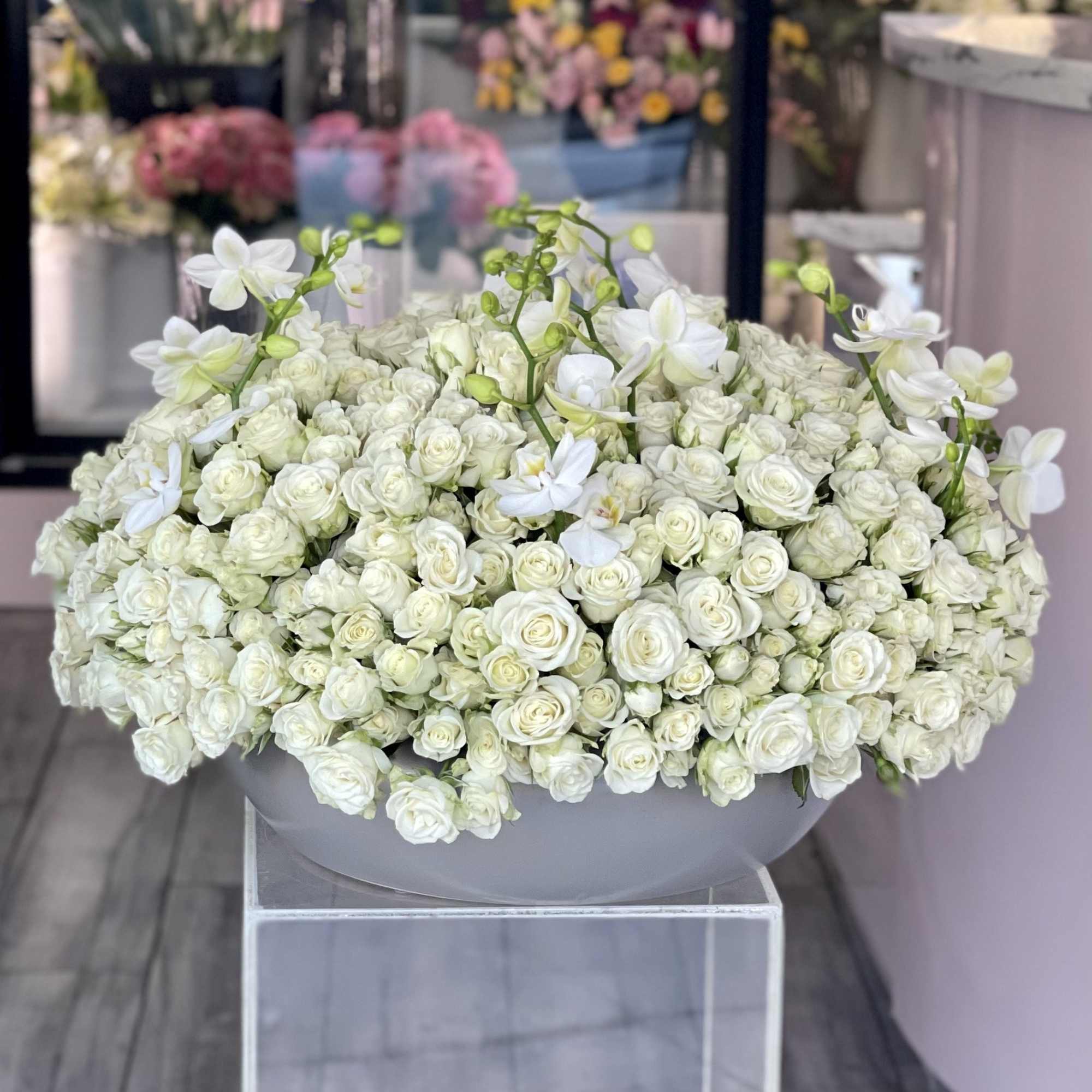 Large white rose arrangement in a gray bowl vase
