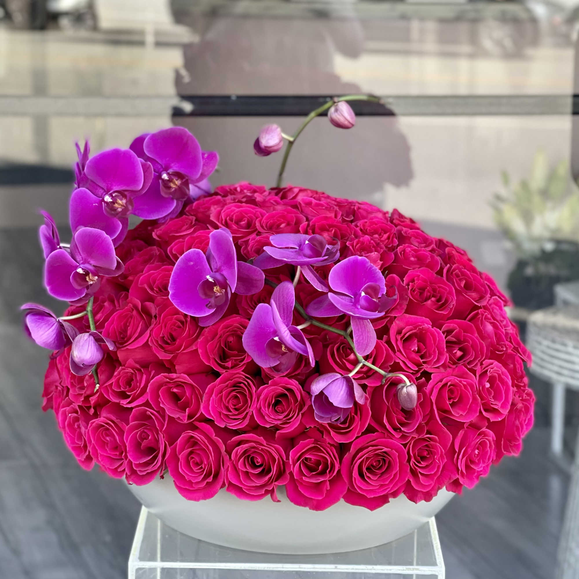 Hot pink rose arrangement with purple orchids in a white bowl vase