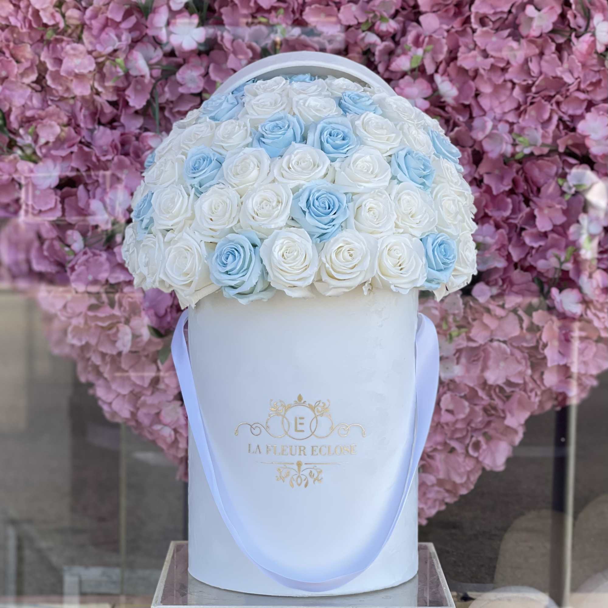 White and blue roses in a white hatbox with ribbon handles