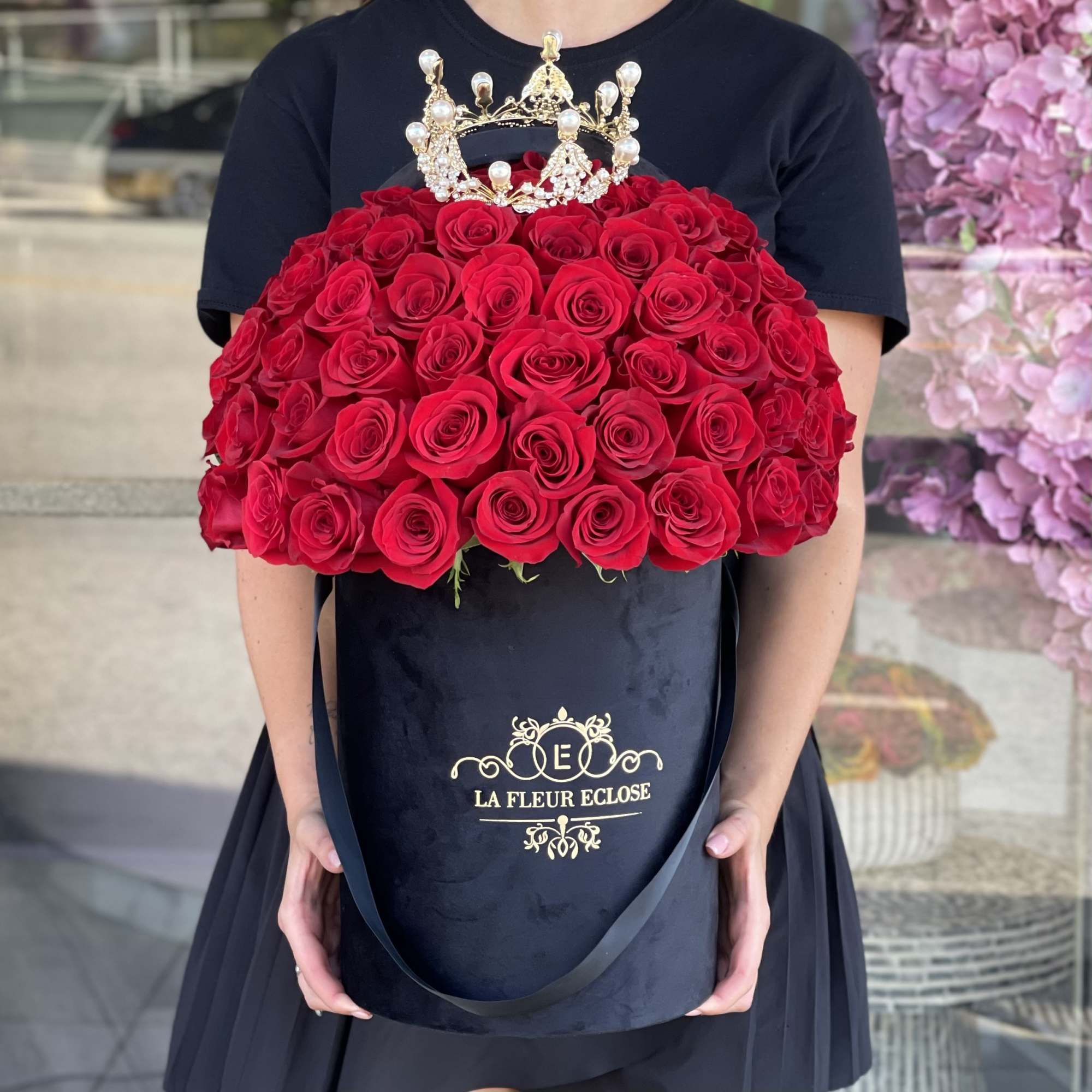 Large red rose arrangement in a black hatbox with a jeweled crown topper