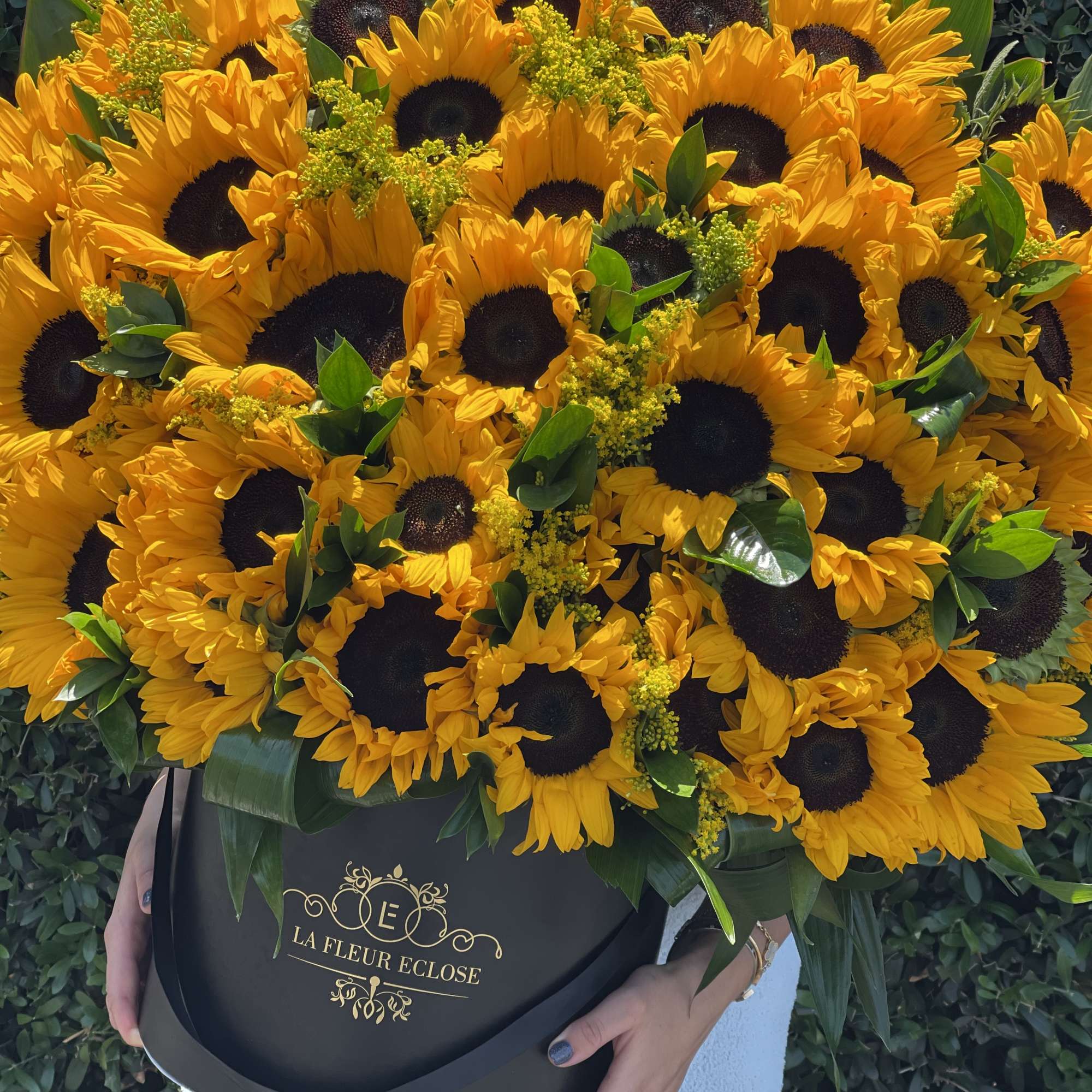 The flower arrangement consists of vibrant sunflowers placed elegantly in a sleek, photo 2 of 2