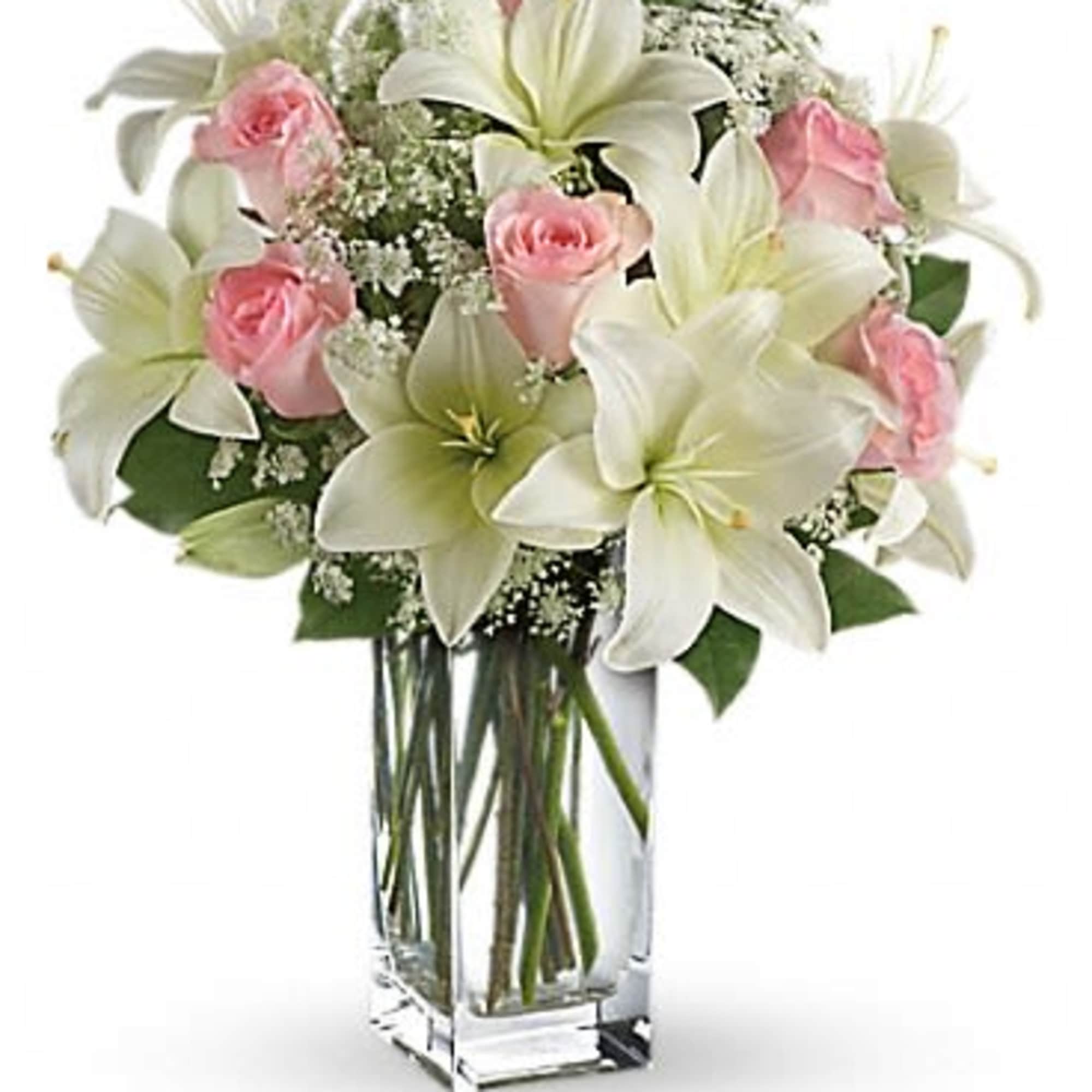 Pink roses and white lilies arranged in a clear glass vase