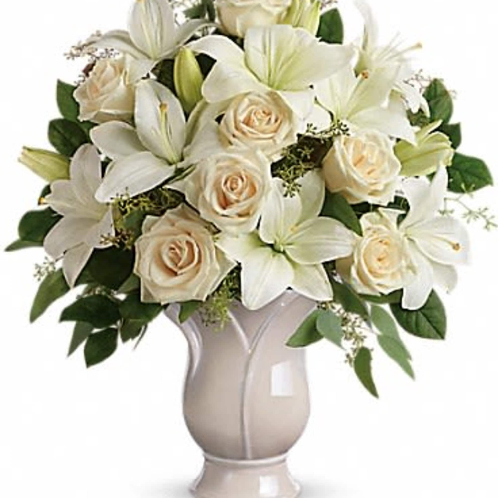 White lilies and cream roses arranged in a beige vase