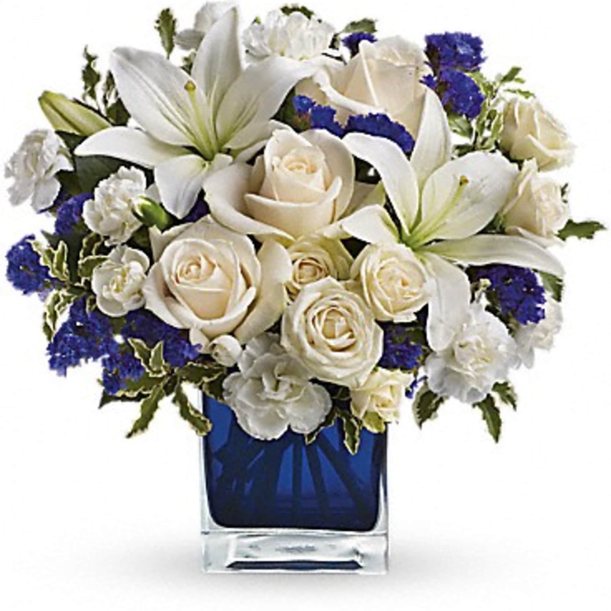 White lilies and roses arranged in a blue glass vase