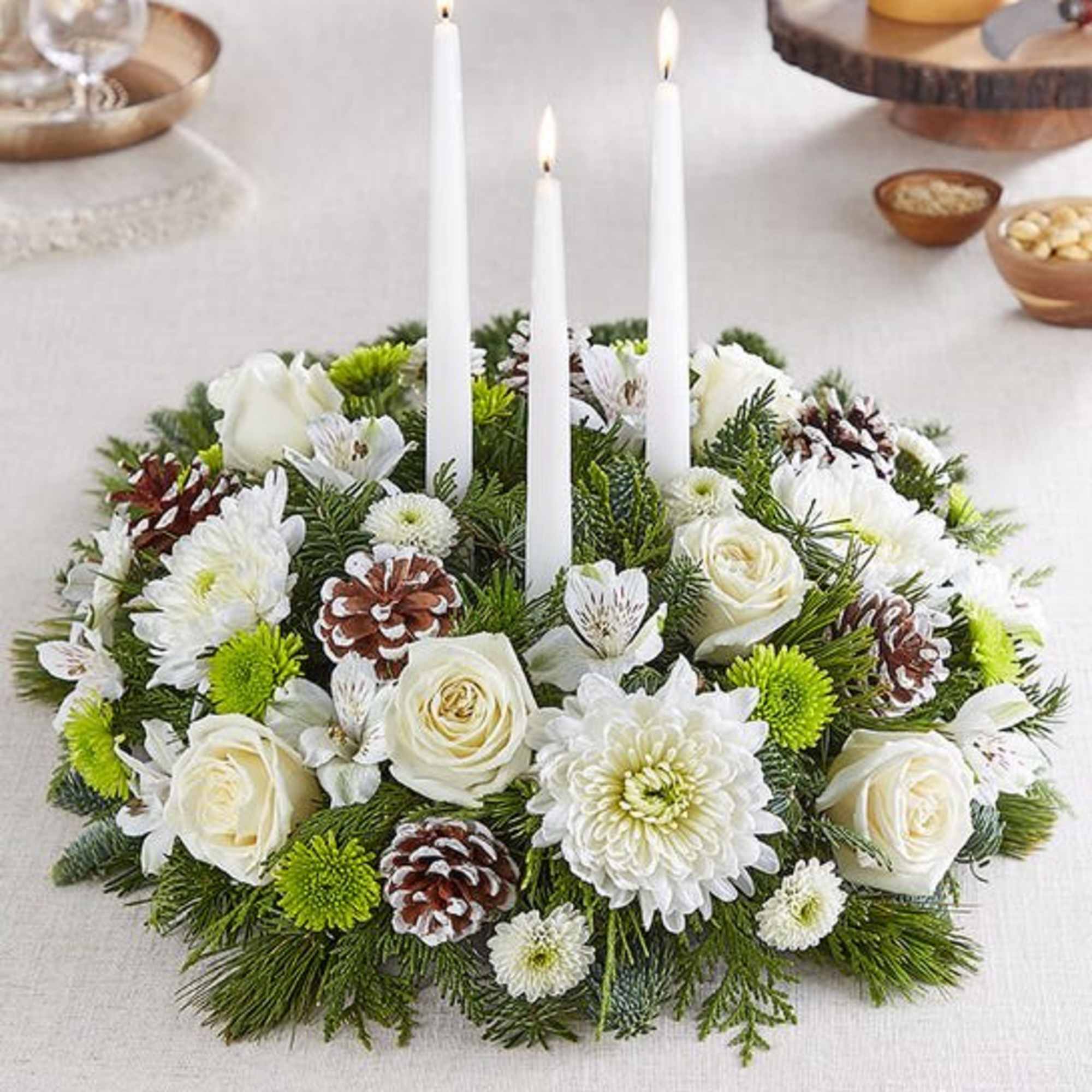 White floral candle centerpiece with pinecones and three taper candles