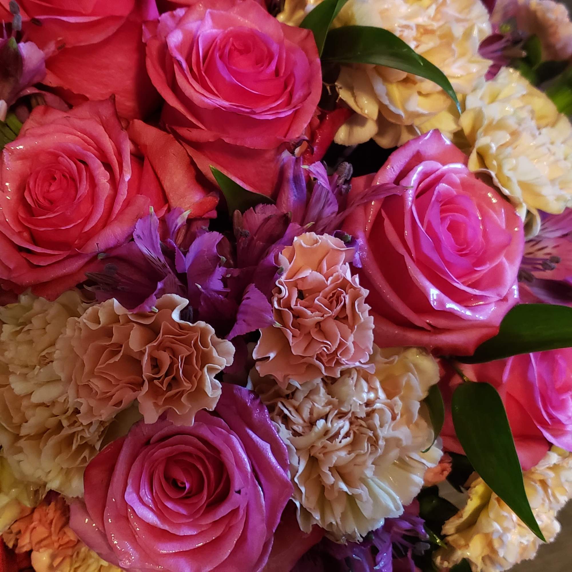Bouquet of pink roses and peach carnations with purple accents