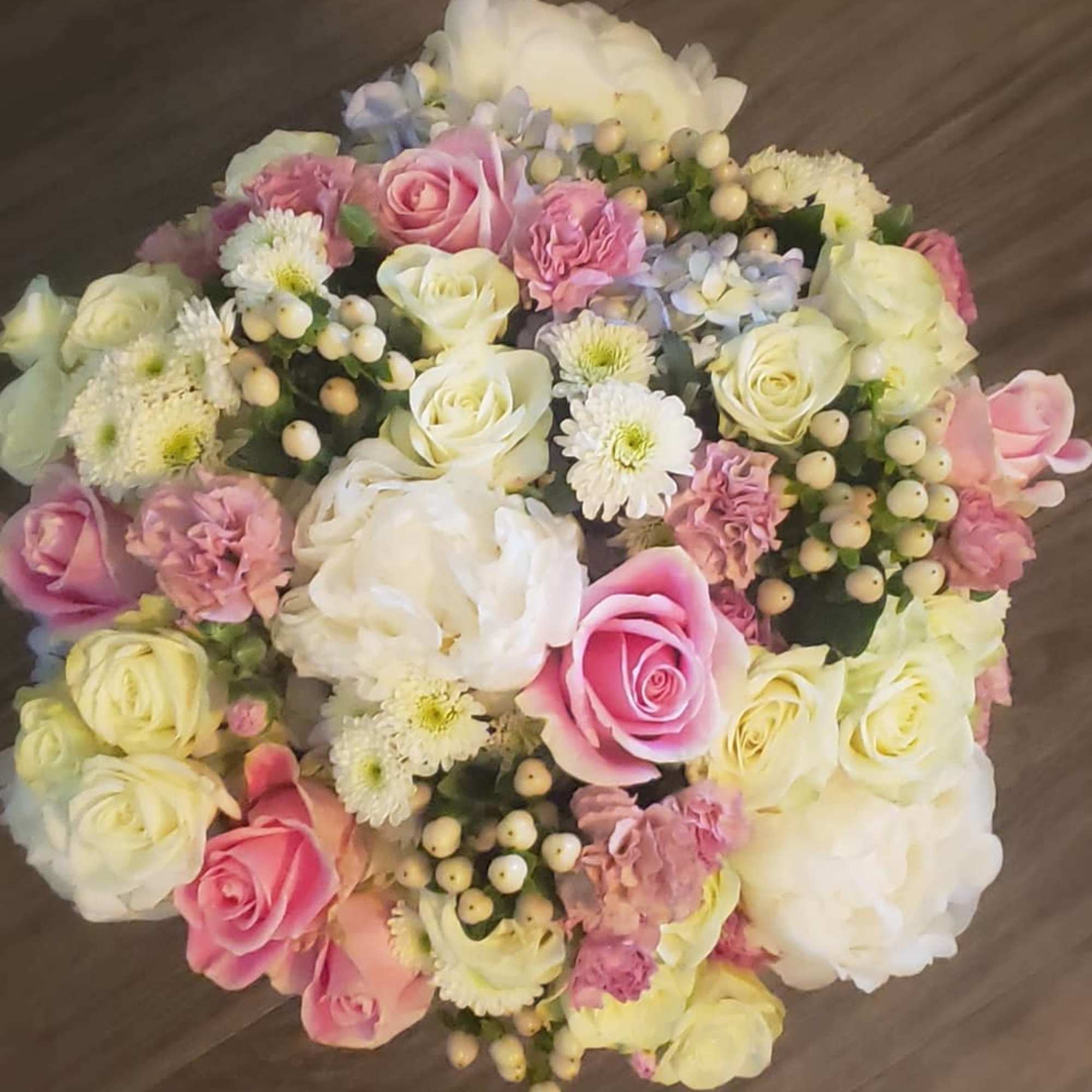 Round bouquet of pink and white roses with small white filler flowers