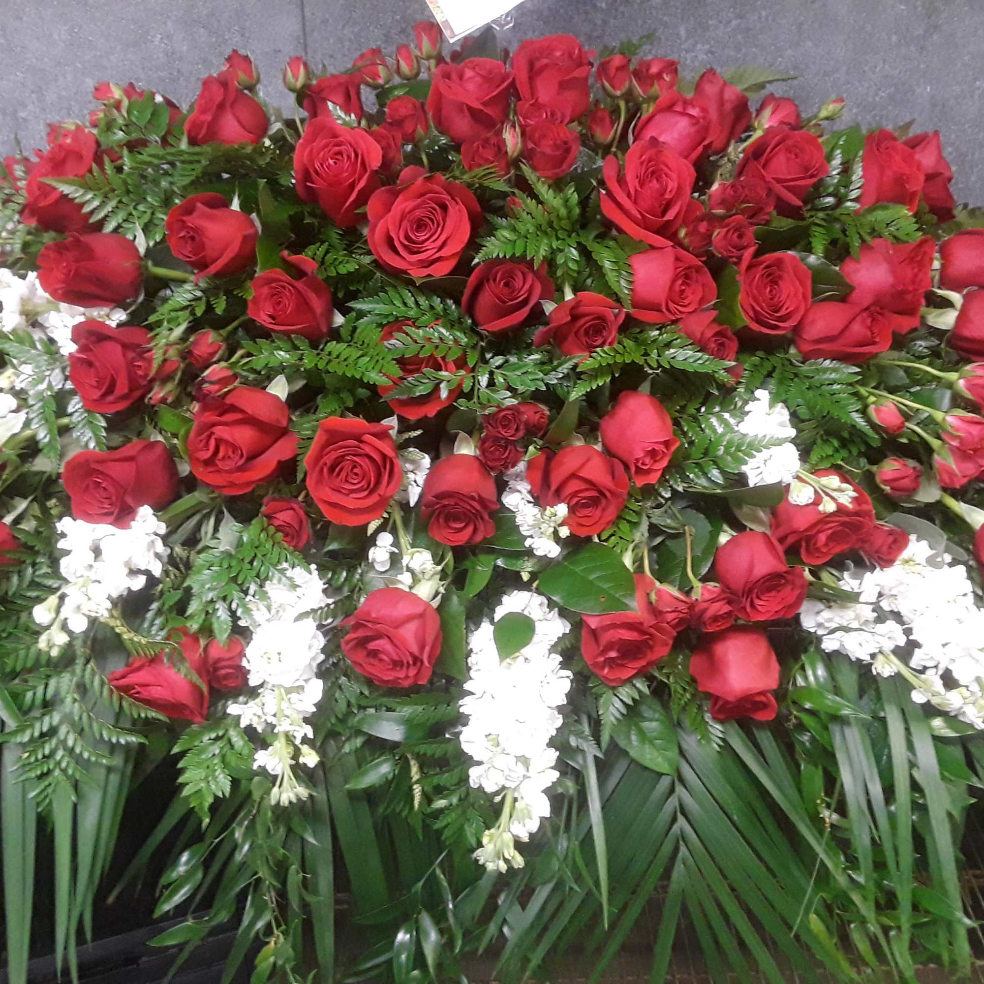 Large arrangement of red roses with white flowers and greenery
