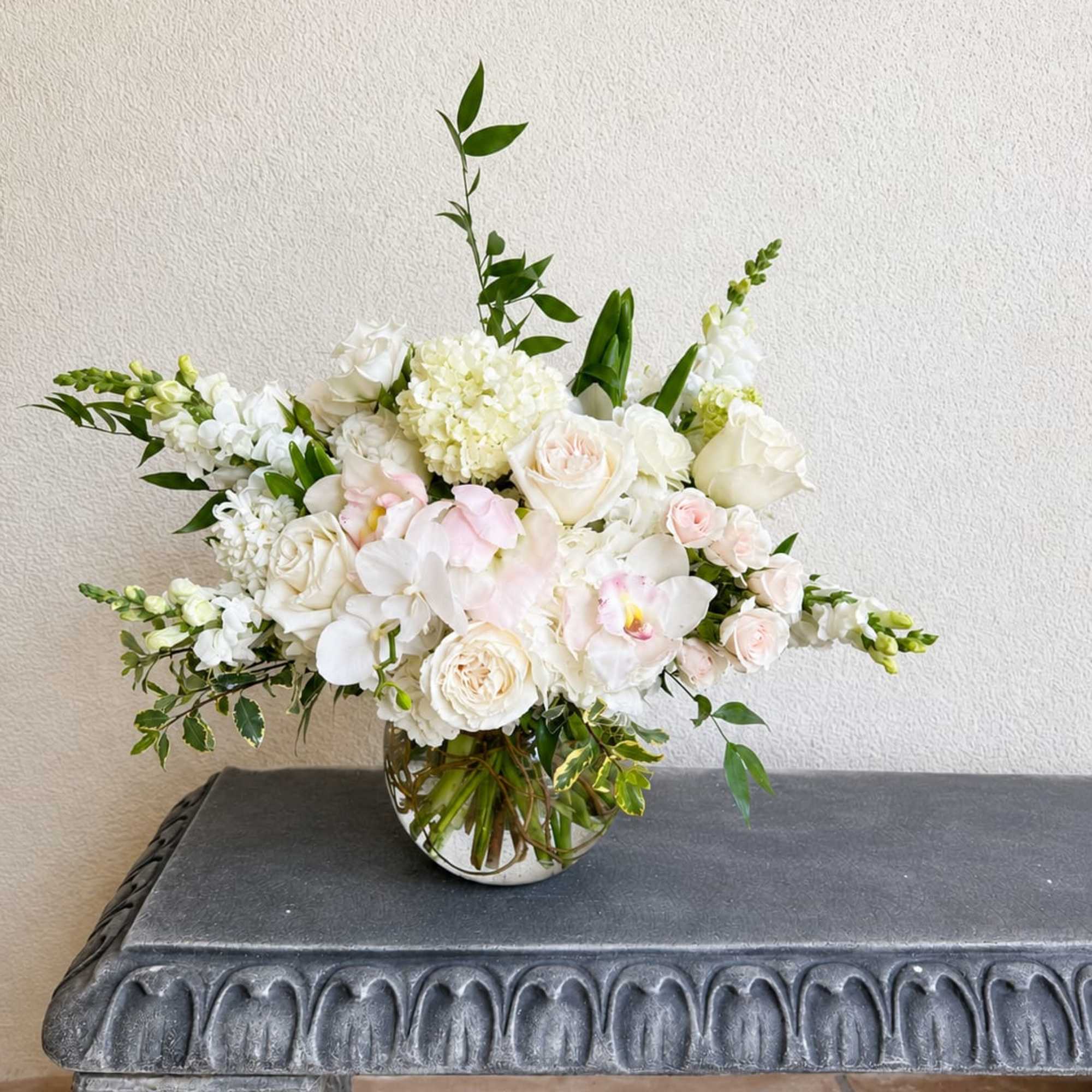 Beautiful round arrangement with a mixture of roses, hydrangeas, spray roses, orchids