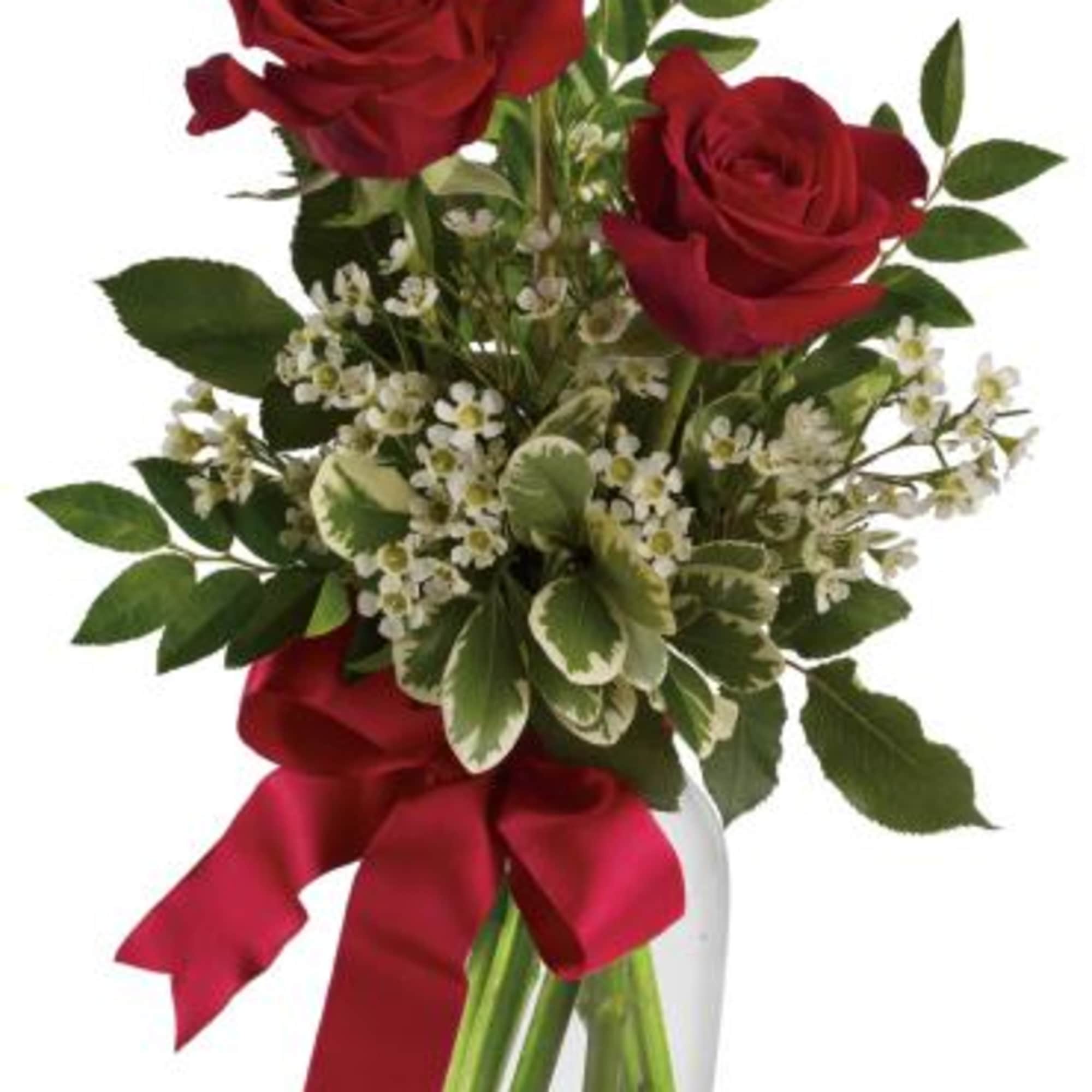 Three red roses with small white blossoms in a clear glass vase tied with a red ribbon