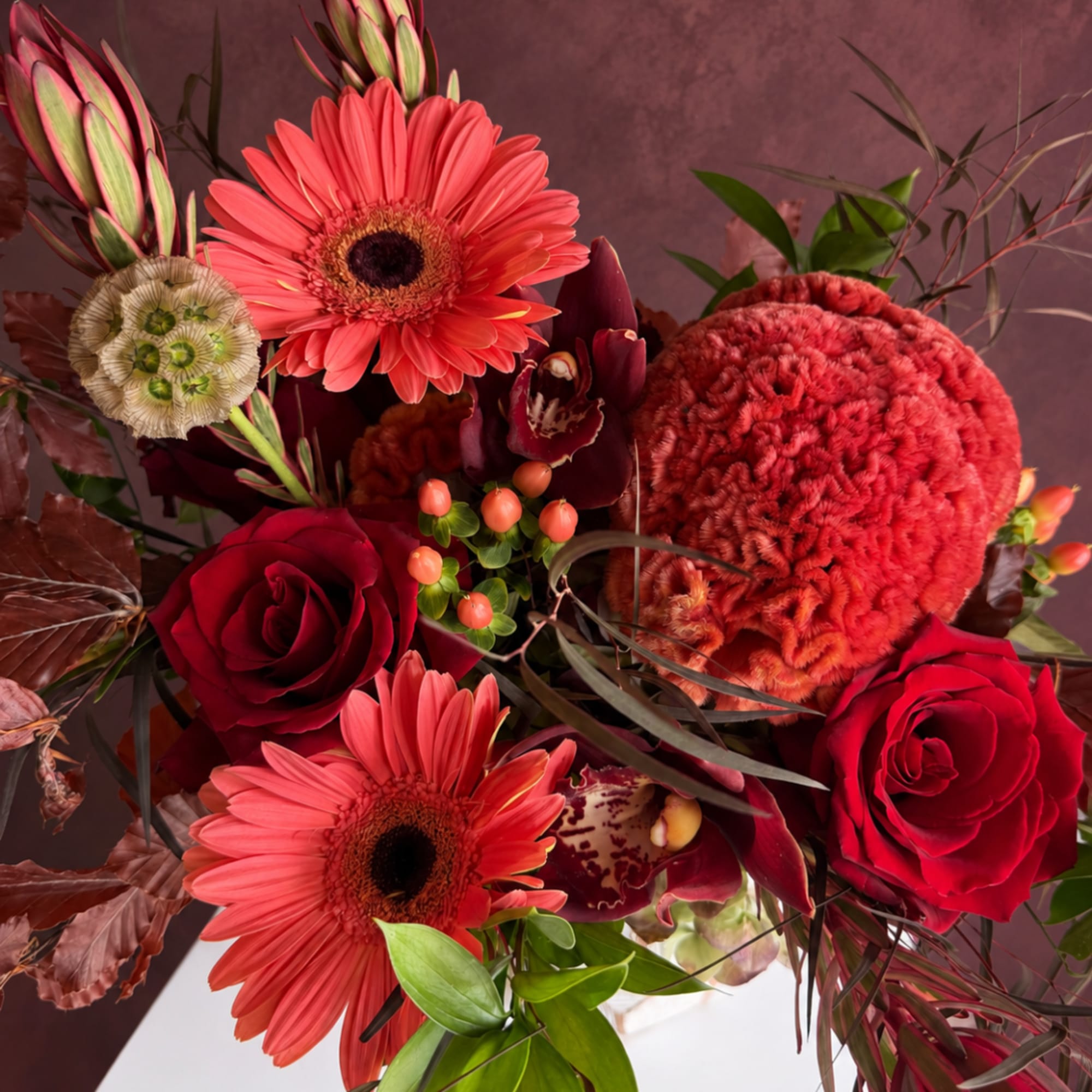 Bouquet with red roses, coral gerbera daisies, and burgundy orchids