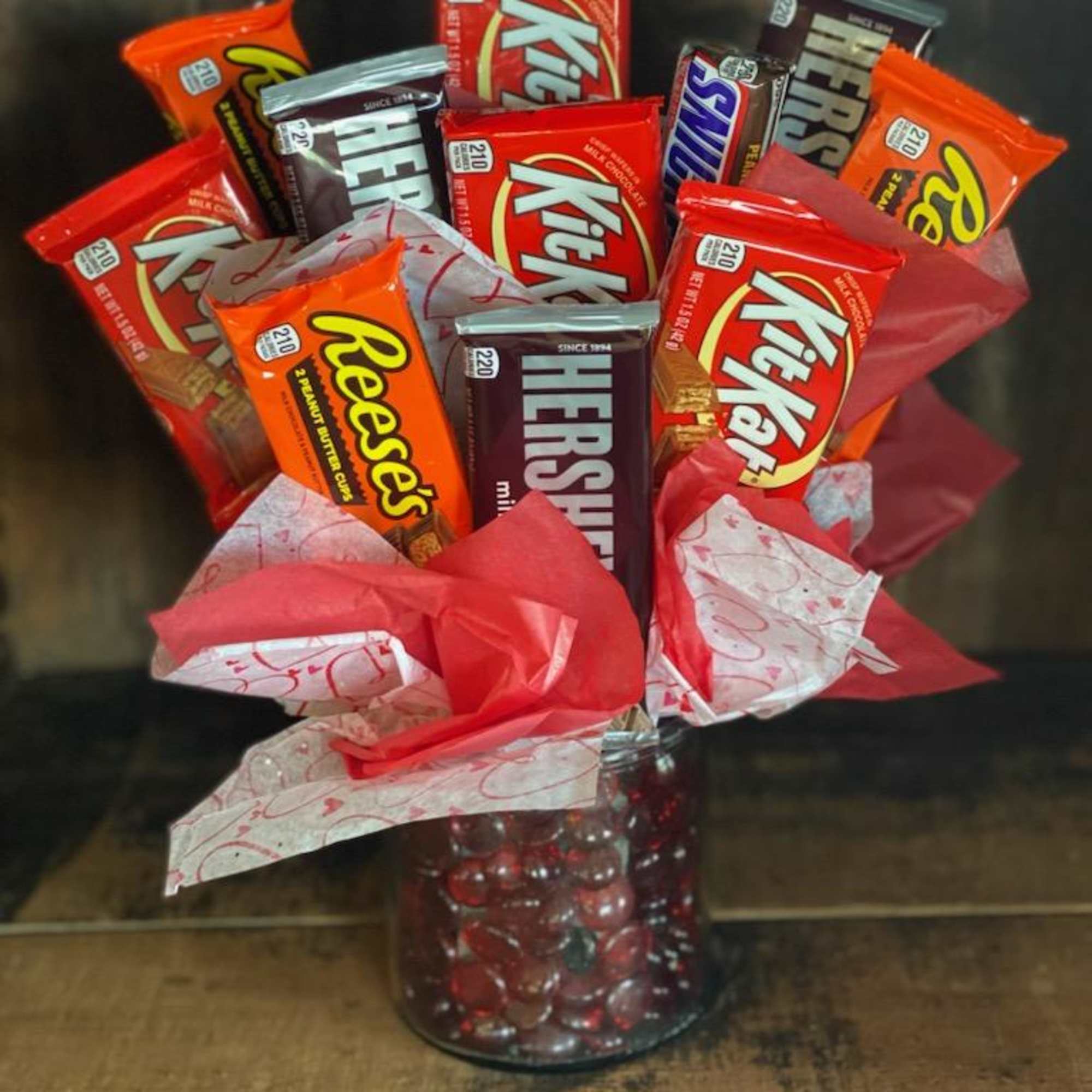 Candy bars arranged in a glass vase with red tissue paper