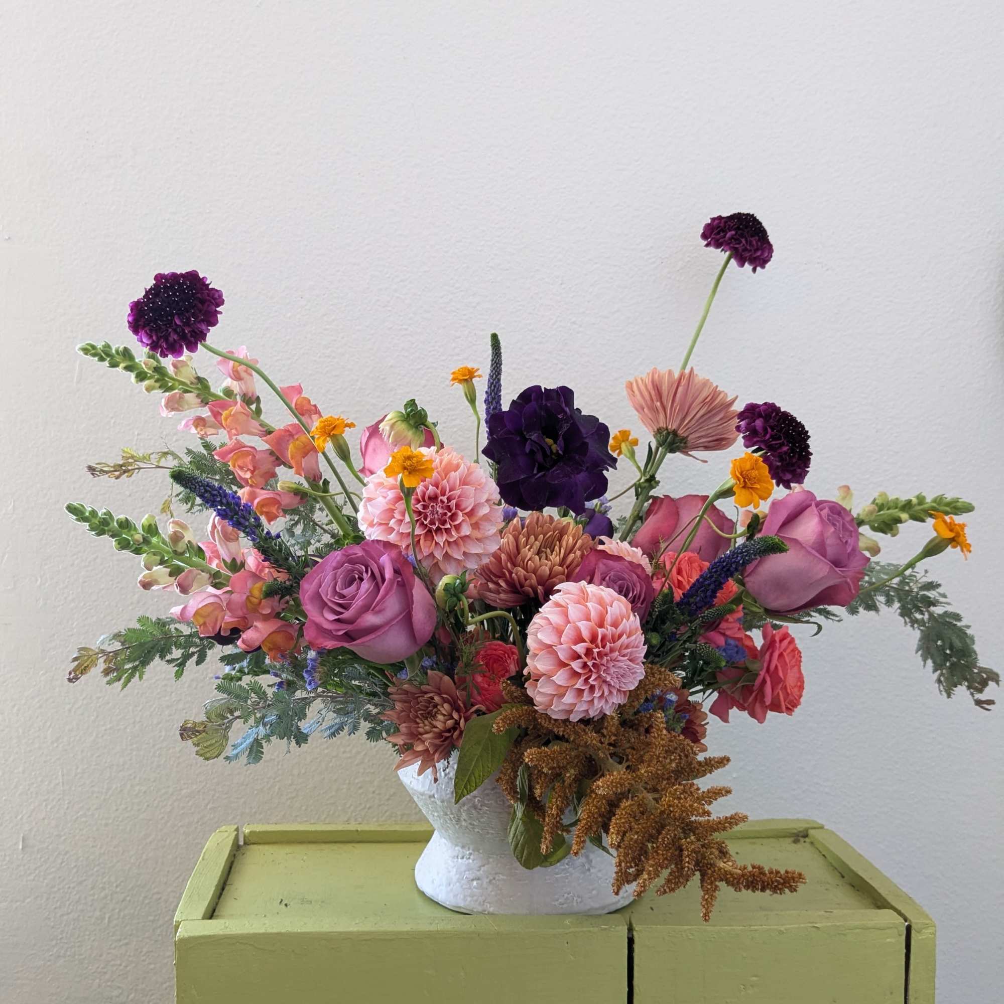Mixed bouquet in a white vase with pink, purple, and peach flowers