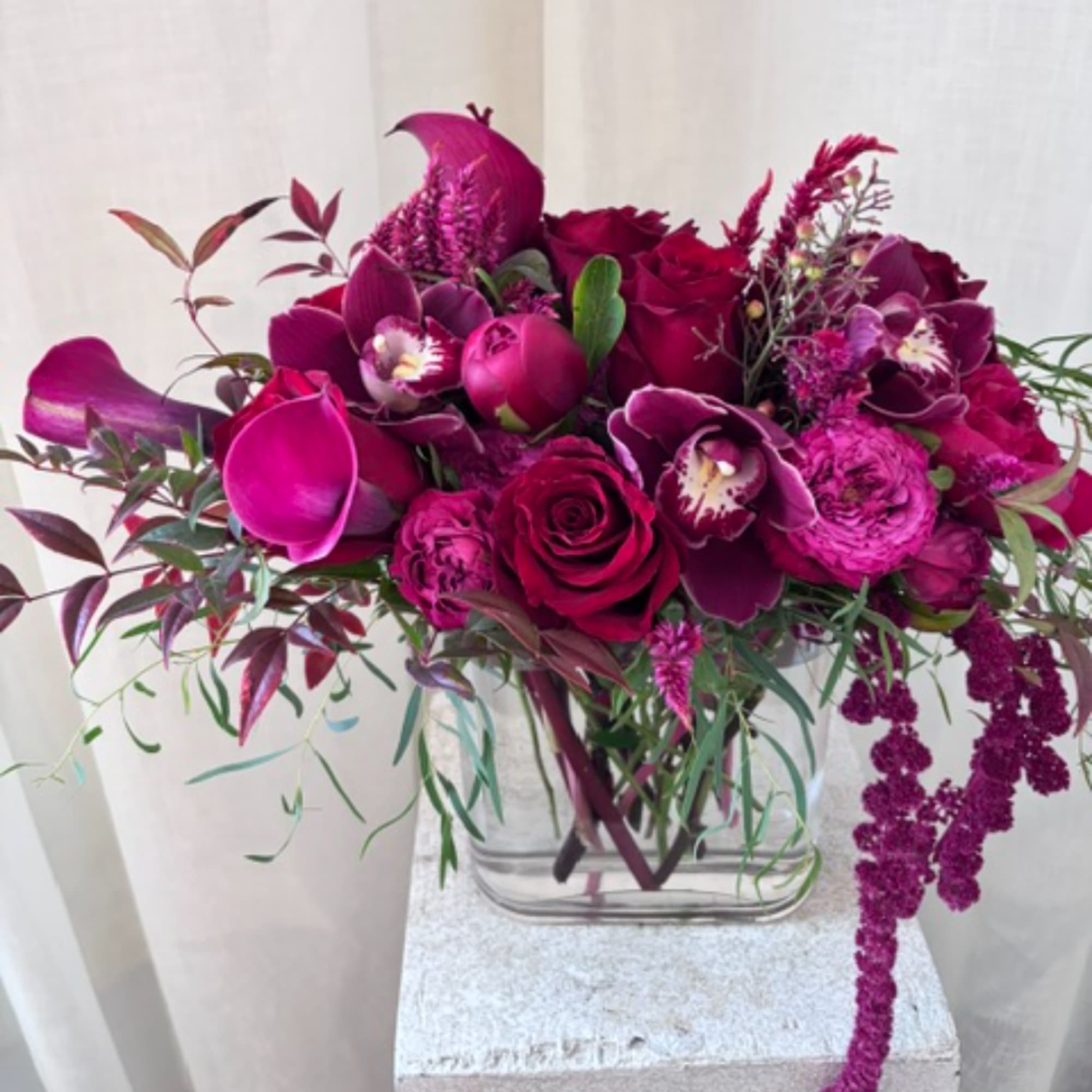 Magenta floral arrangement in a clear square vase