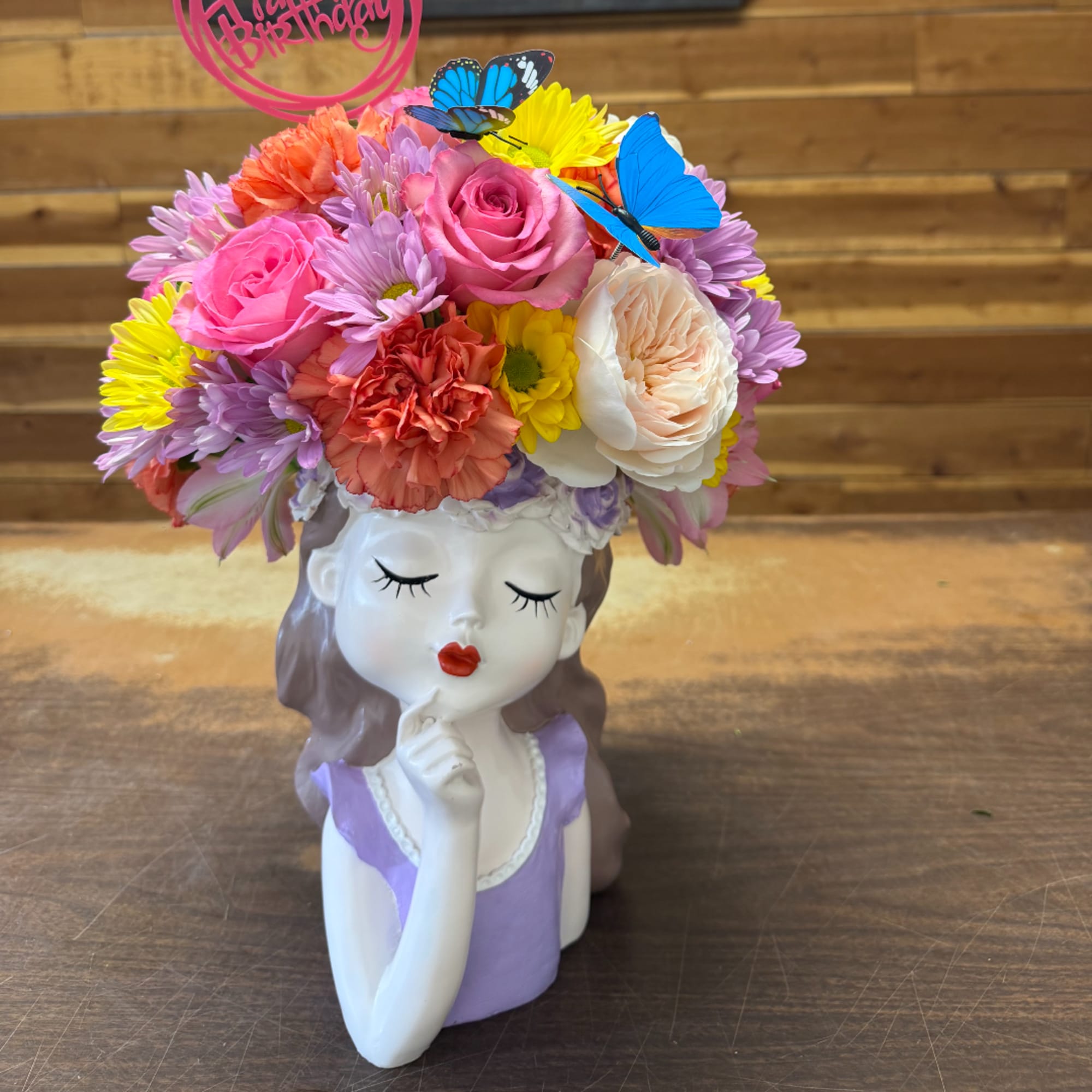 Colorful flower arrangement in a decorative girl-shaped vase with butterfly picks, photo 2 of 2