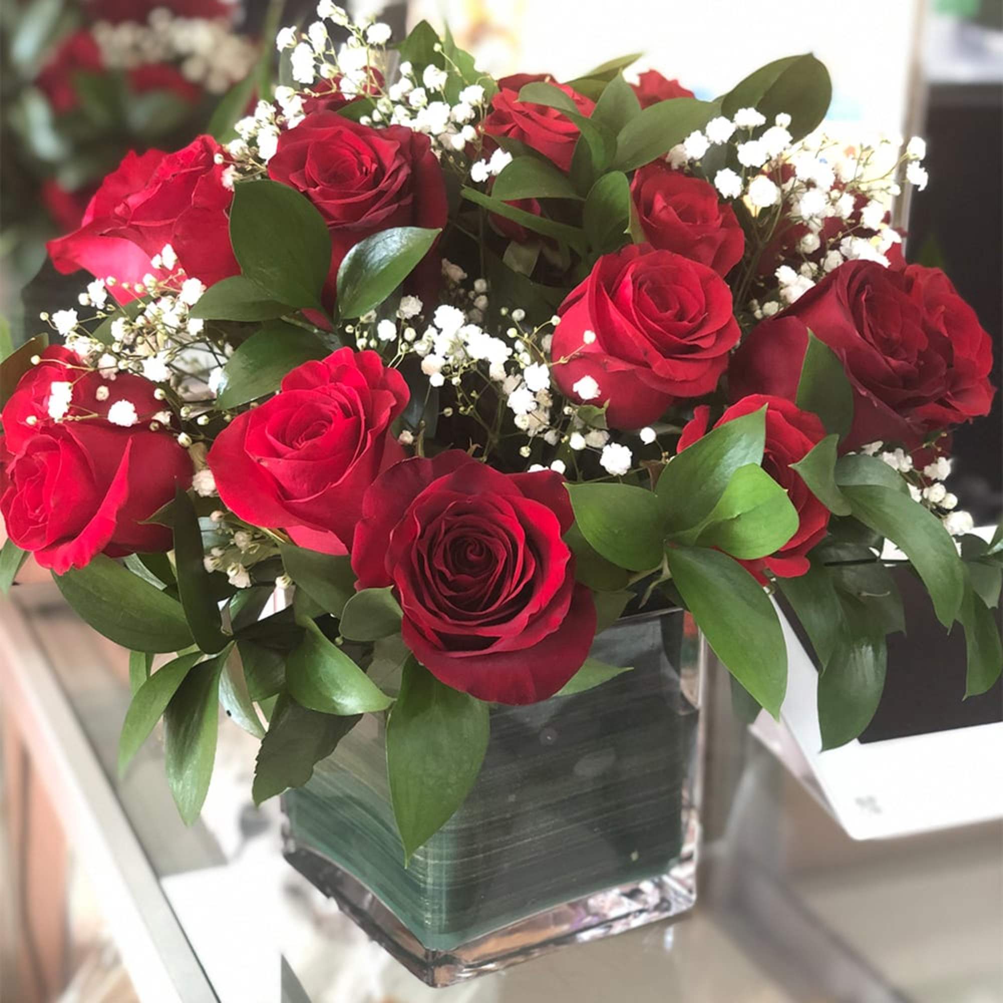 Red roses in a square glass vase with white baby's breath