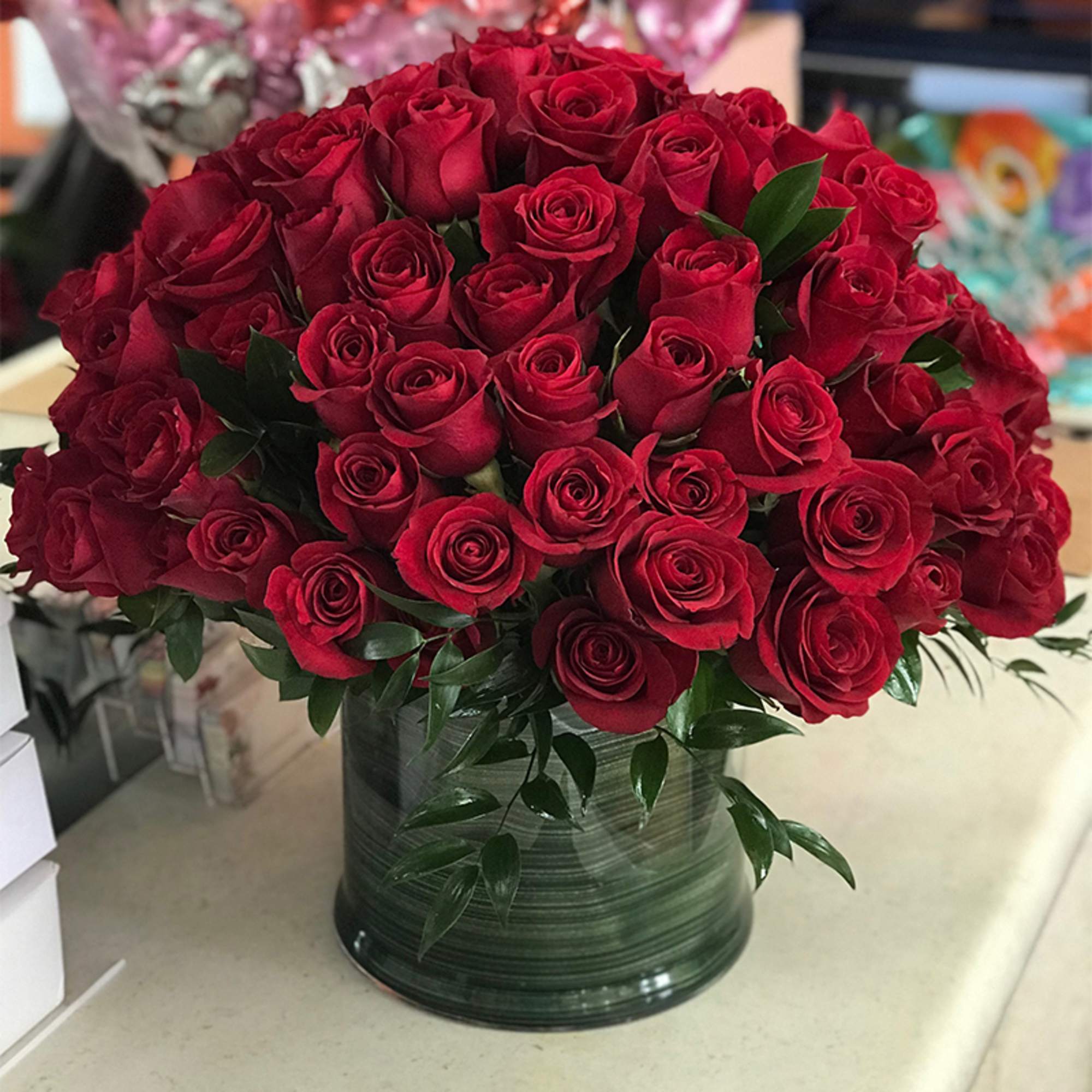 A large bouquet of red roses in a dark green vase