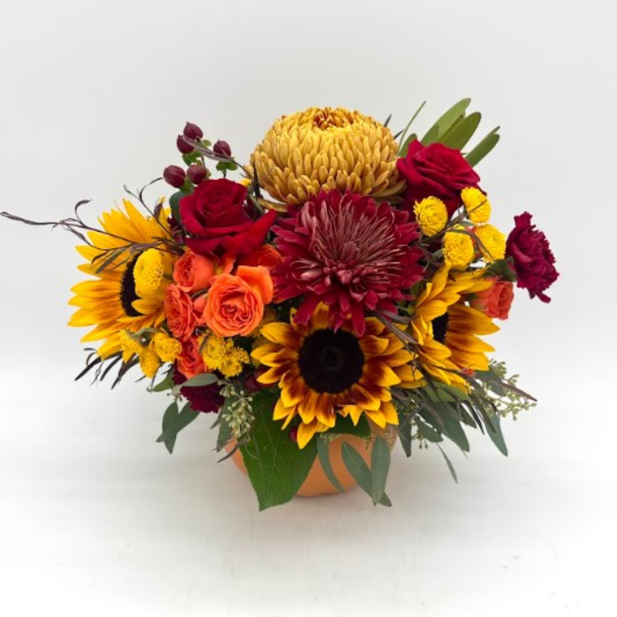 Bouquet of sunflowers, red roses, and orange blooms in a vase