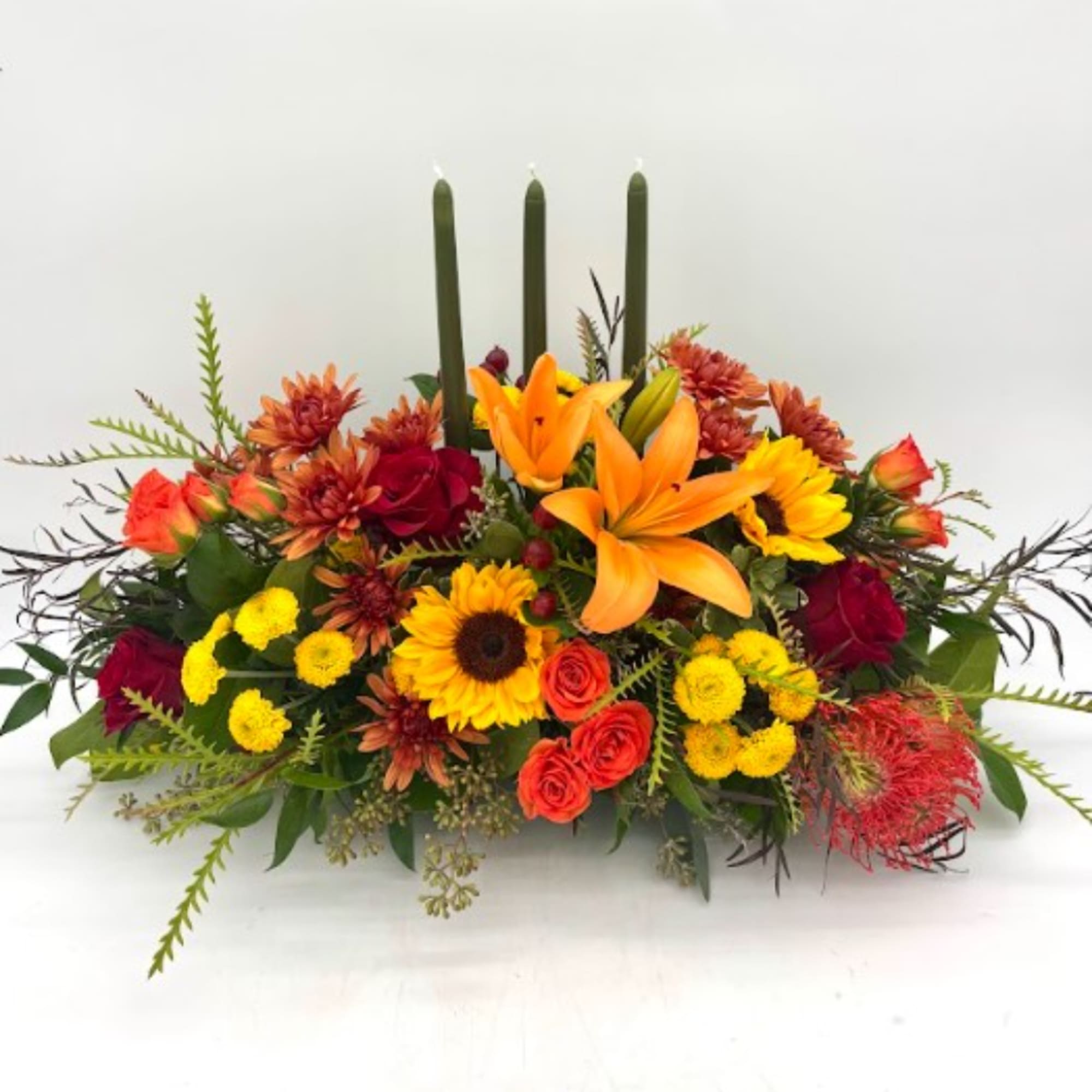 Colorful floral centerpiece with candles and mixed blooms in a low arrangement