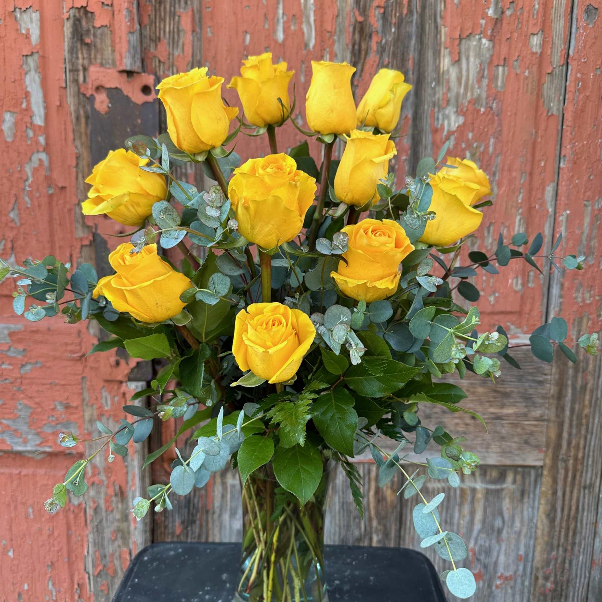 Yellow roses in a clear glass vase with eucalyptus