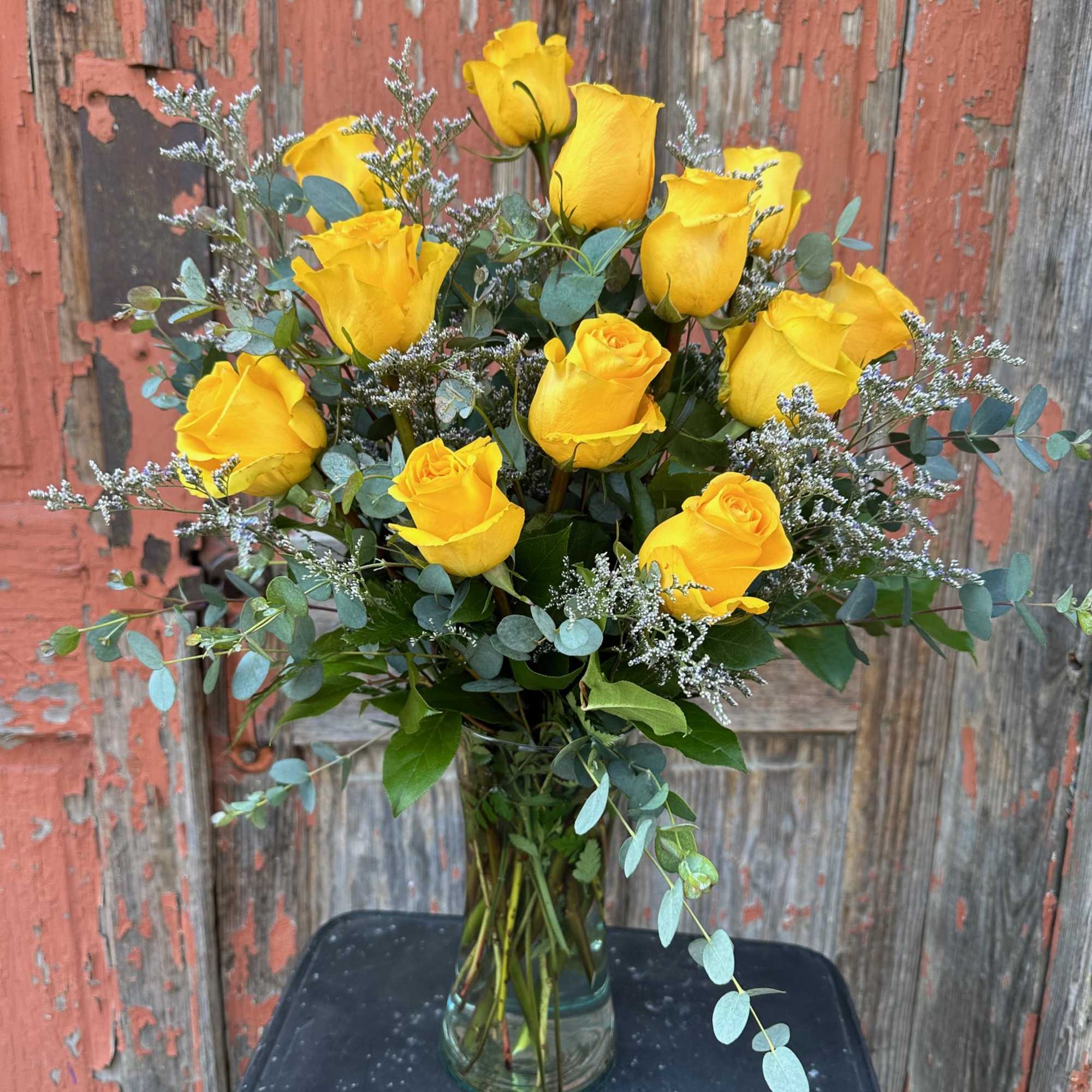 Yellow roses arranged in a clear glass vase with airy filler