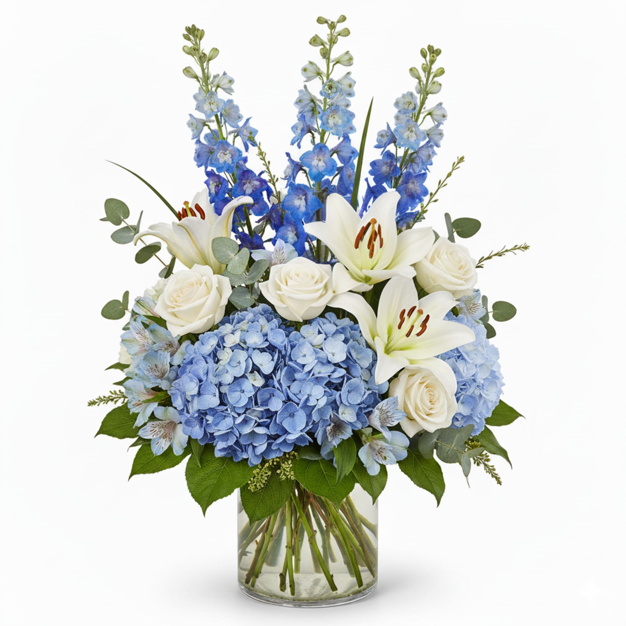 Blue hydrangeas, white roses, and lilies in a glass vase