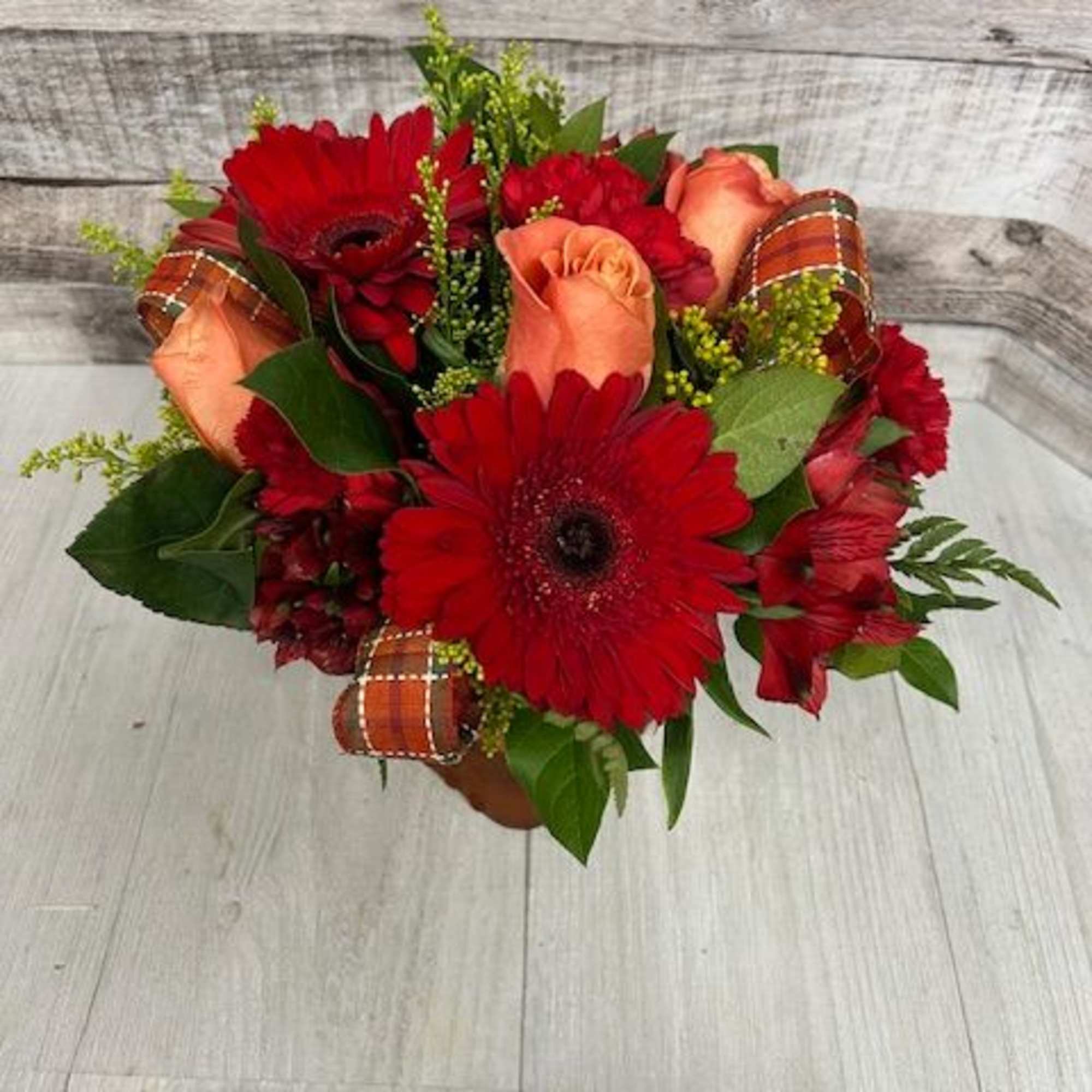 Bouquet of red gerbera daisies and peach roses with plaid ribbon accents