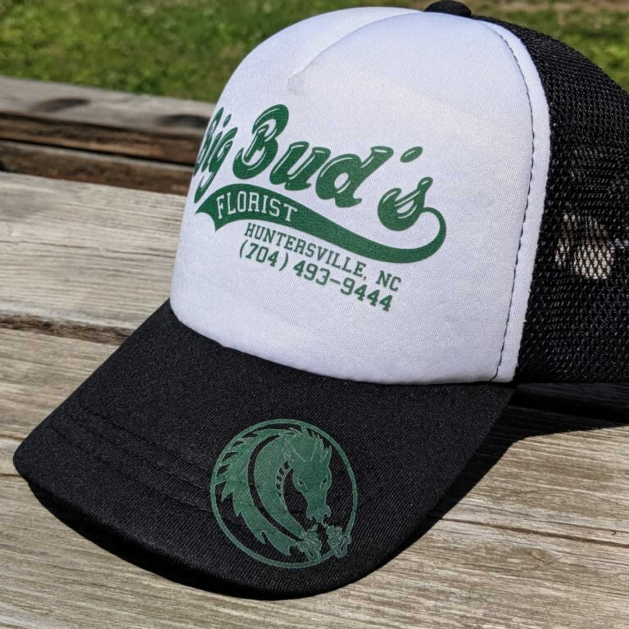 Black and white trucker hat with green florist logo text