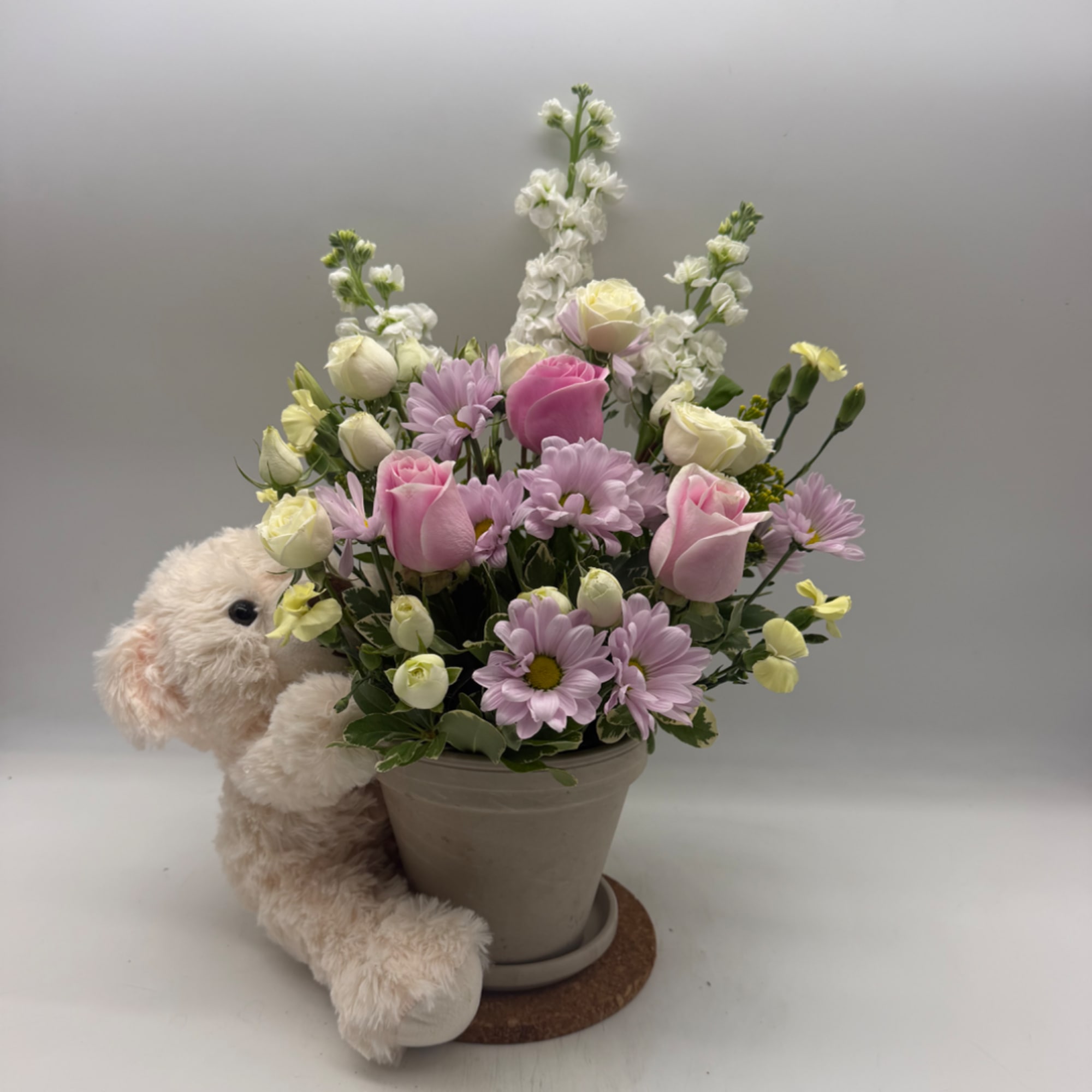 Pink and white mixed bouquet in a gray pot with a plush bunny