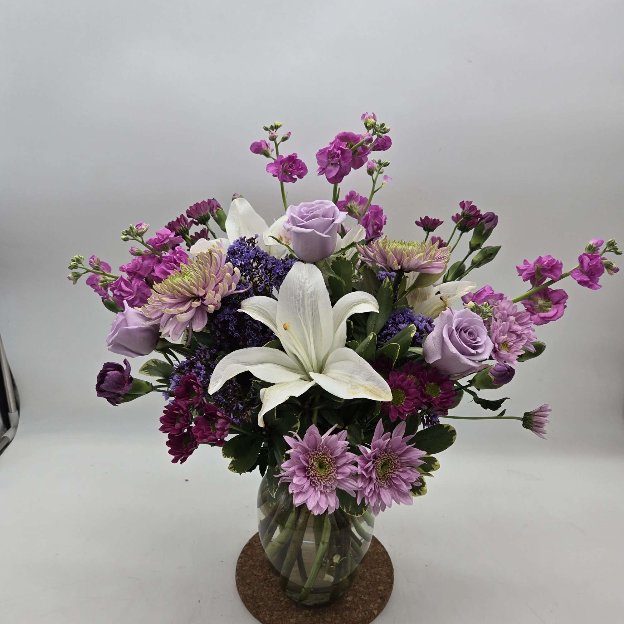 Soft lavender roses and airy daisy-like blooms tumble around two prominent white