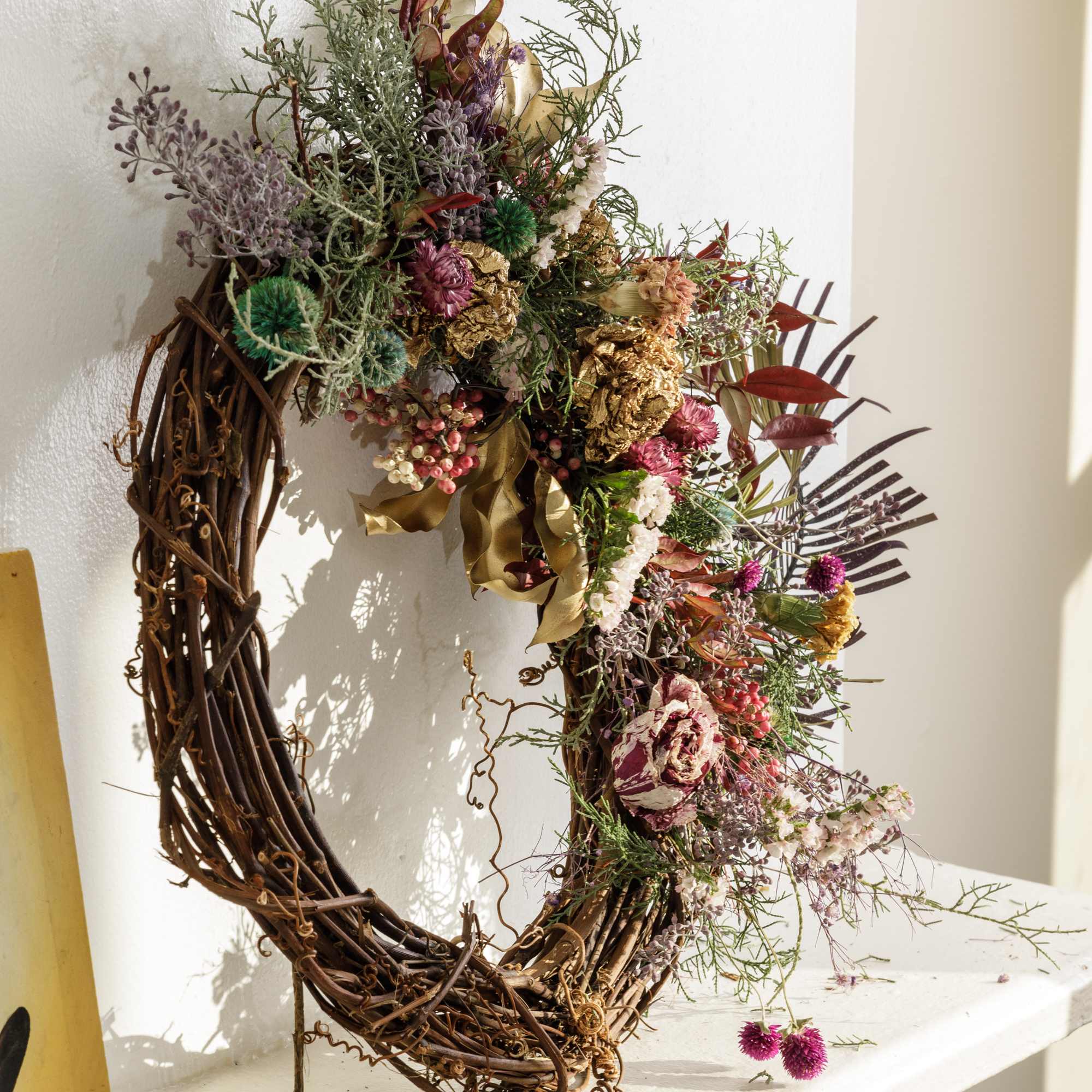 Floral wreath with dried flowers and gold accents on a grapevine base
