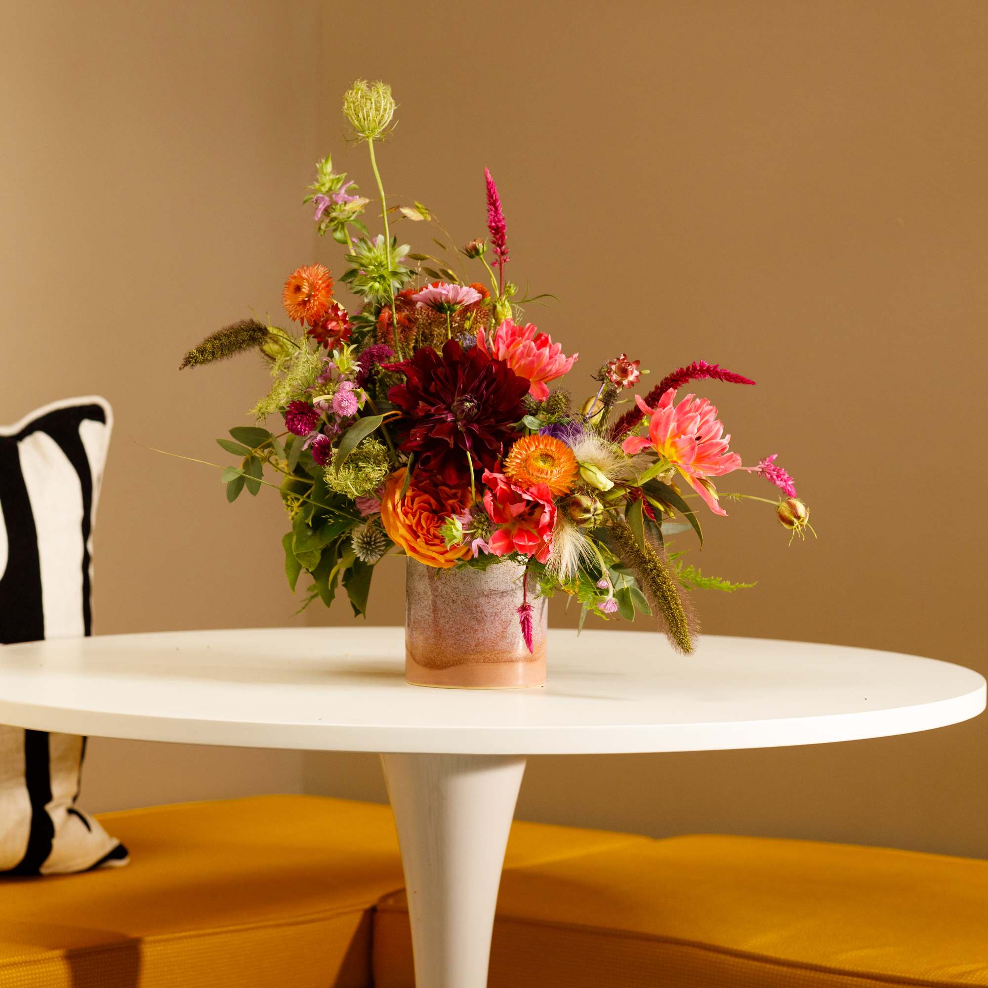 Colorful mixed bouquet in a small glass vase on a white table