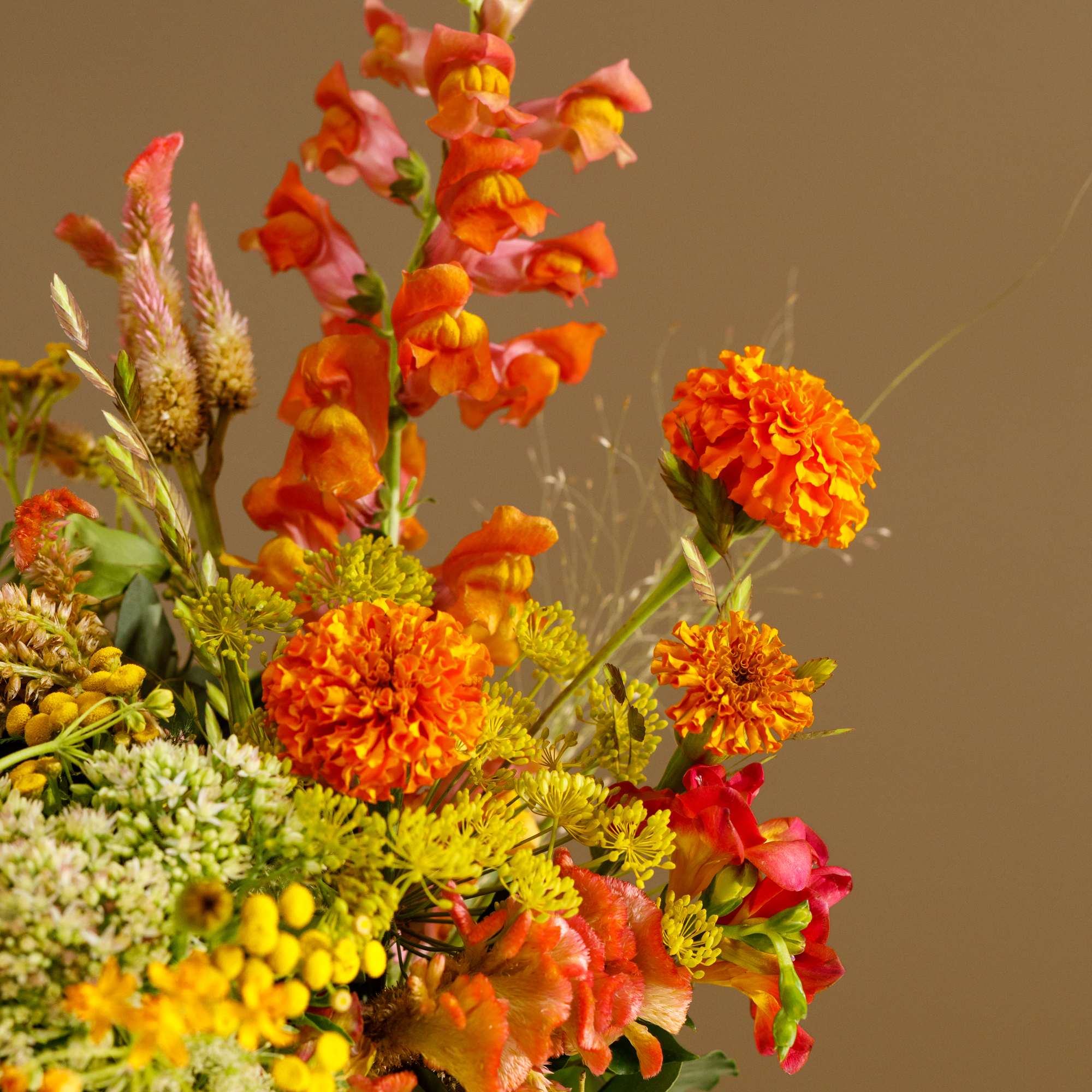 Bright orange and yellow floral arrangement in a low container