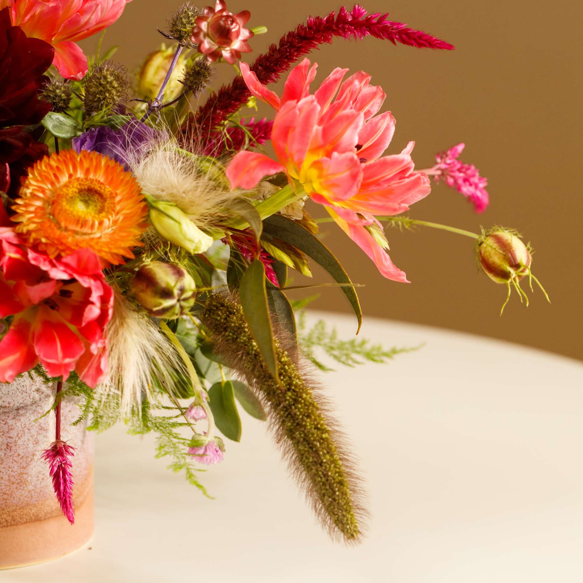 Bright mixed flower arrangement in a speckled vase