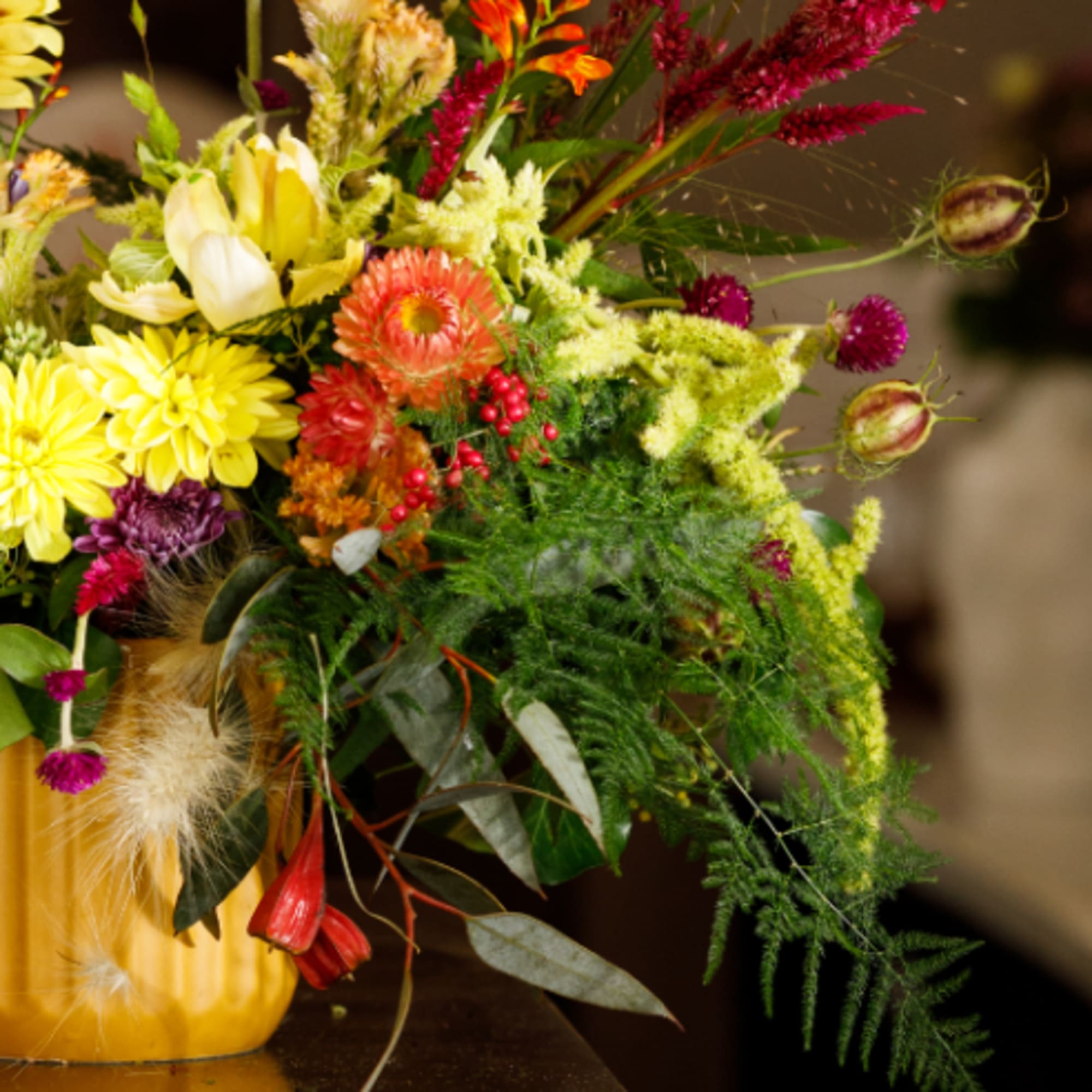 Colorful mixed bouquet in a yellow vase with long trailing stems